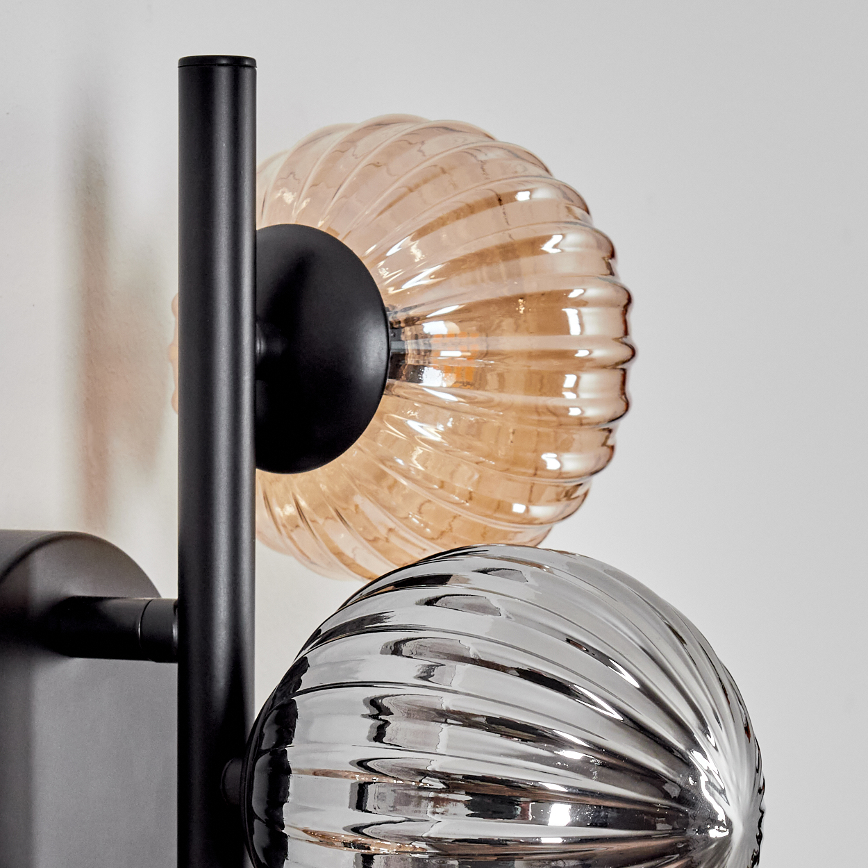 Wandlampe mit drei blasenartigen Glaskolben, schwarzem Rahmen, weißem Hintergrund.