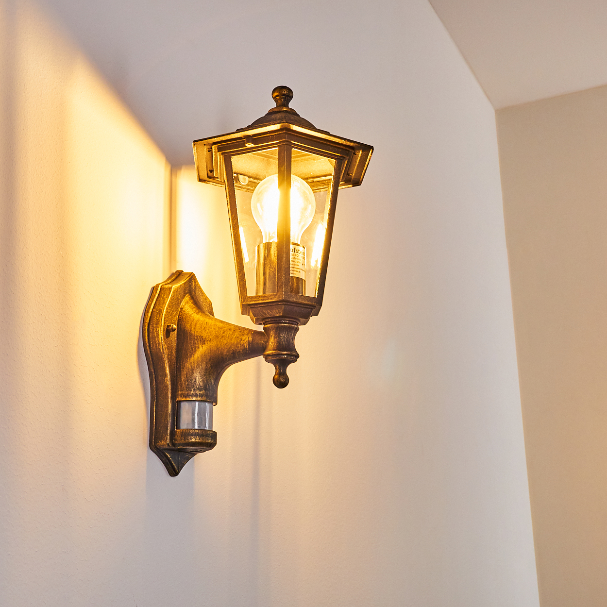 Bronze-Außenwandleuchte. Das Licht beleuchtet die Wand. Weißer Wandhintergrund.