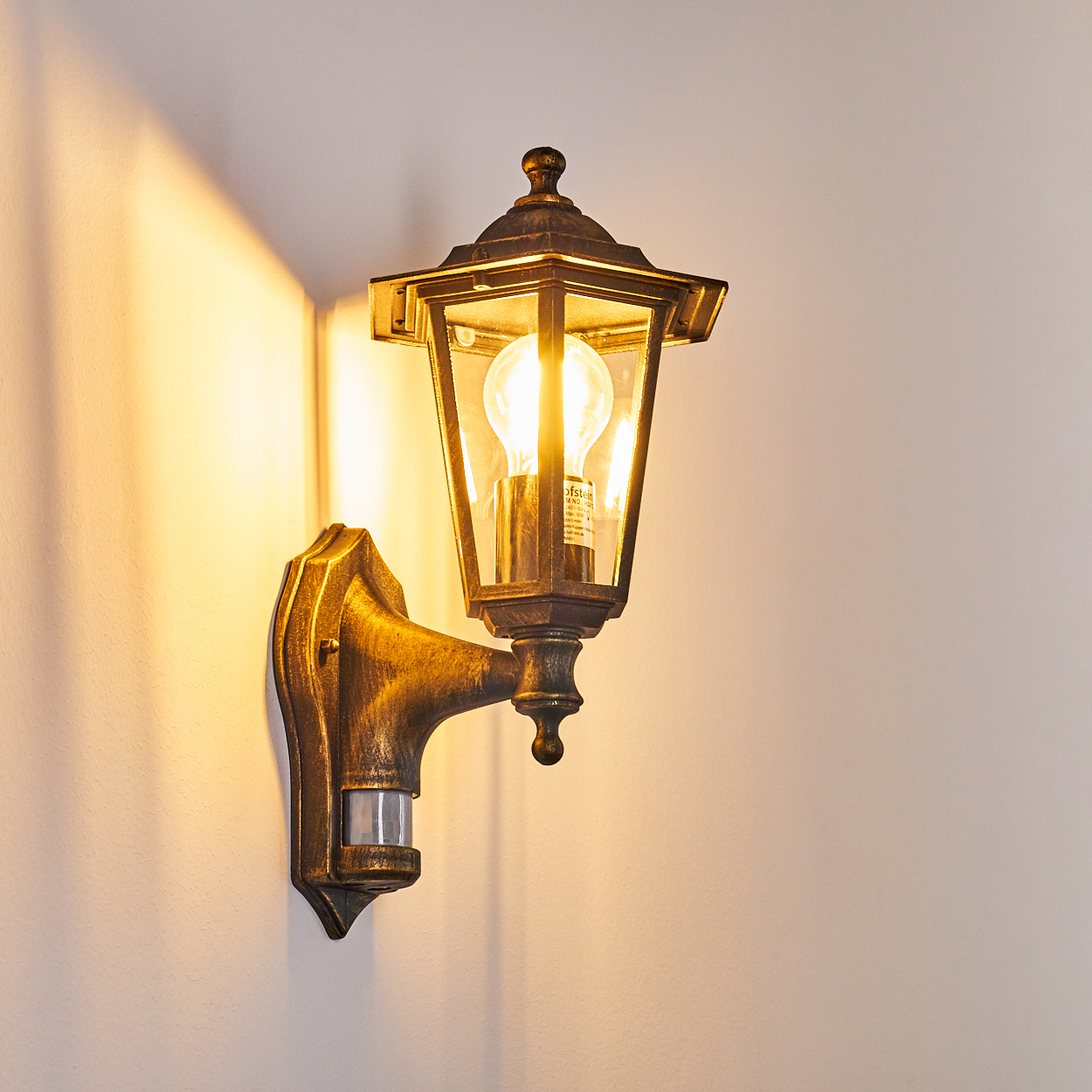 Bronze-Außenwandleuchte. Das Licht ist an und beleuchtet die Wand.
