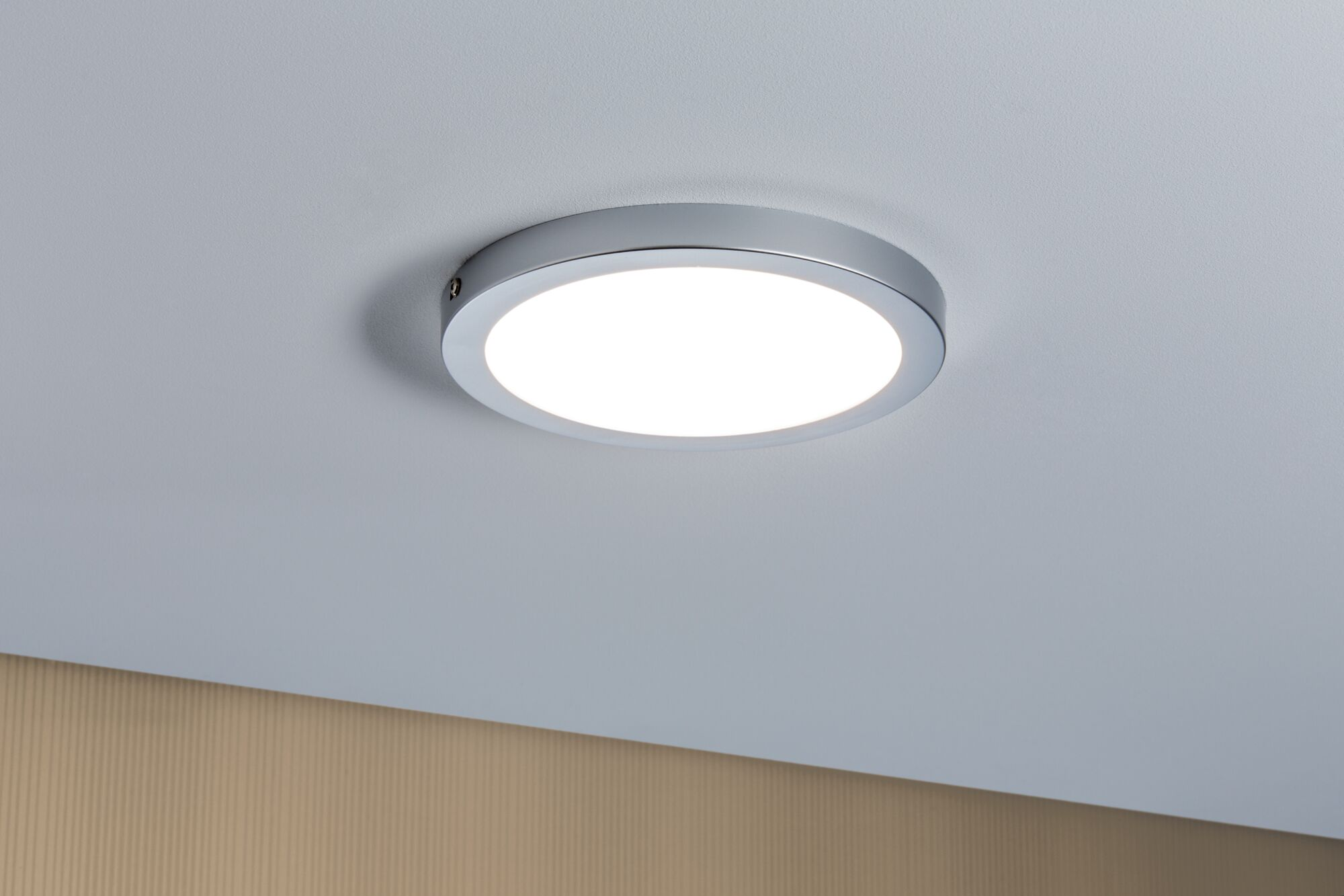 Okrągła, srebrna lampa sufitowa, z jasnym, białym światłem.