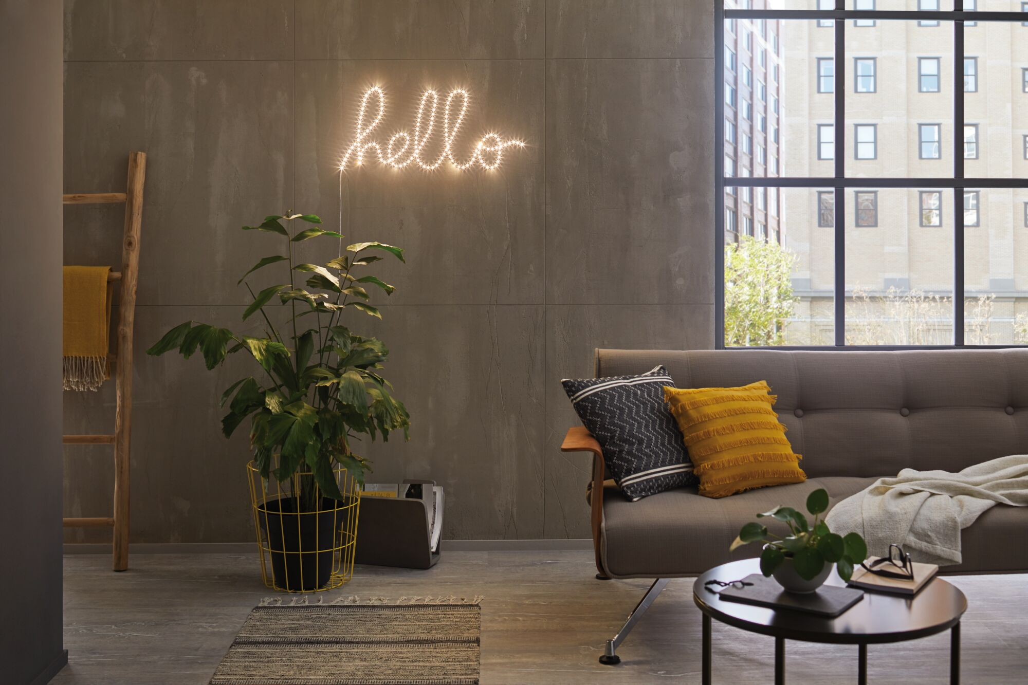 Wohnzimmer mit Neon "hello", Pflanze, Leiter und Sofa.