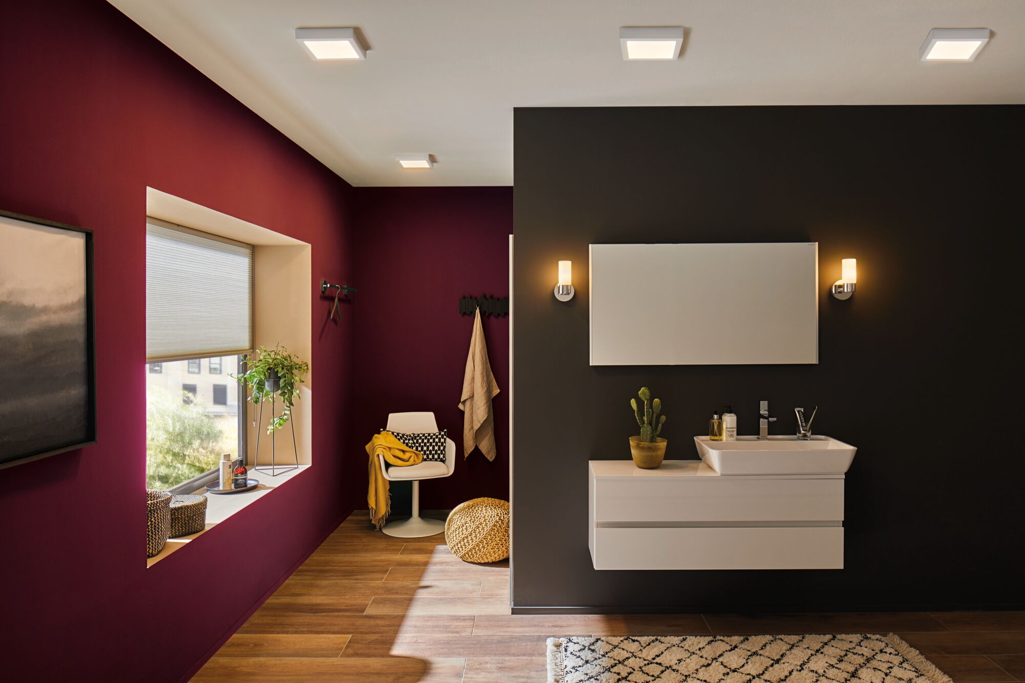 Bagno con finestra, specchio, lavandino e cactus.