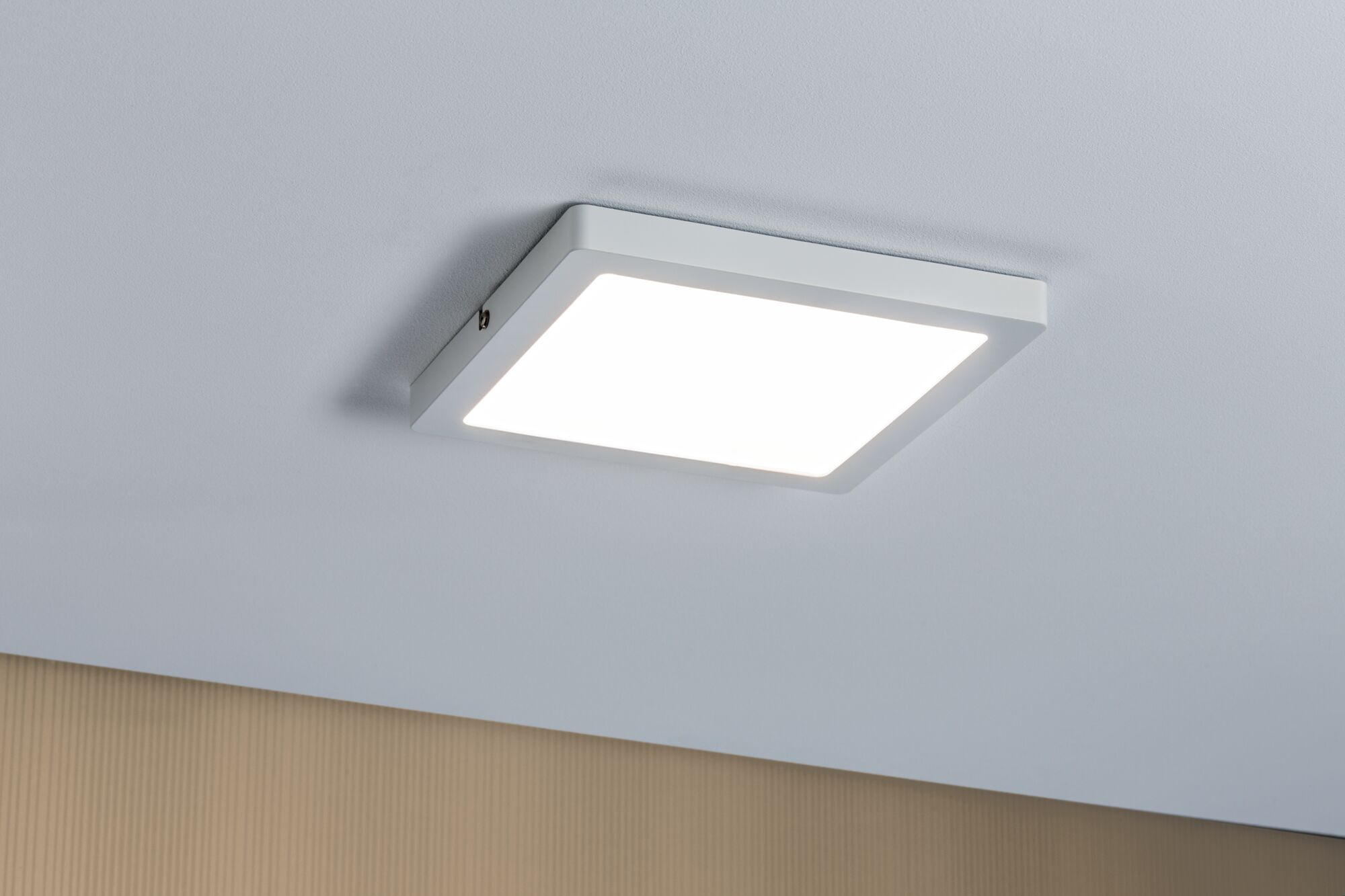 Plafoniera quadrata bianca montata su un soffitto bianco. La luce è accesa.