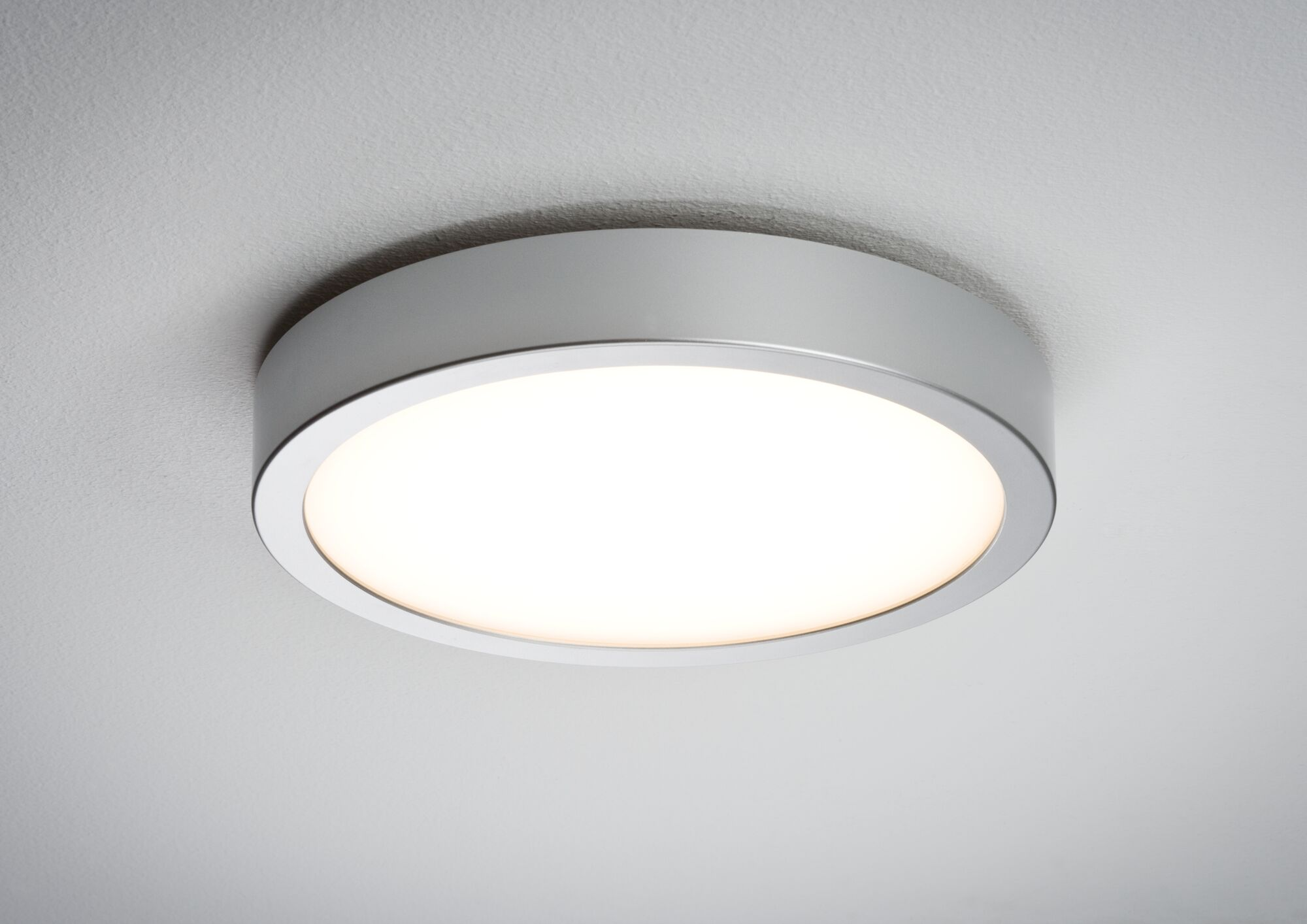 Runde, silberne LED-Deckenleuchte. Das Licht ist an, an einer weißen Decke.