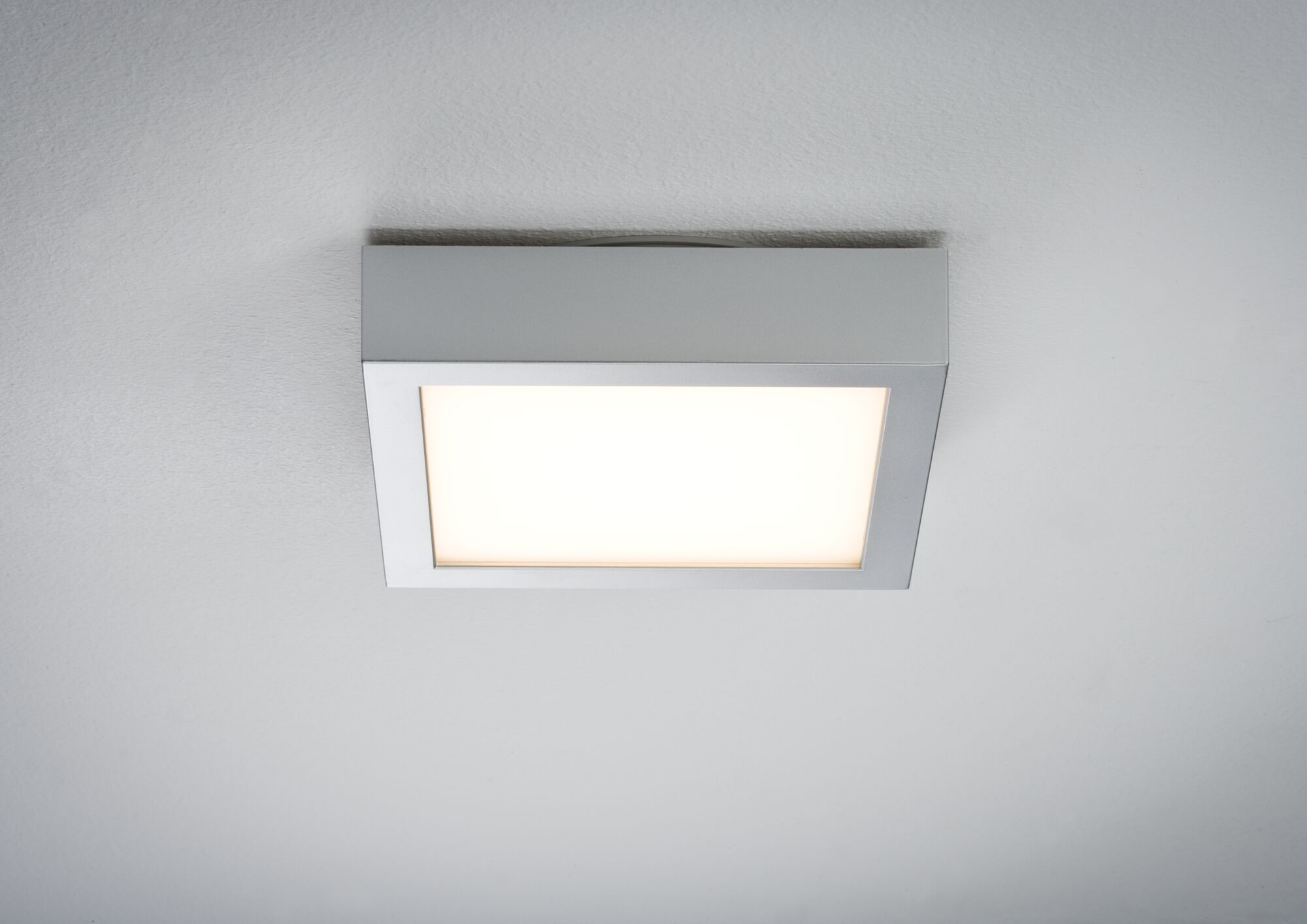 Una plafoniera LED quadrata con cornice argentata e luce bianca, vista dal basso.