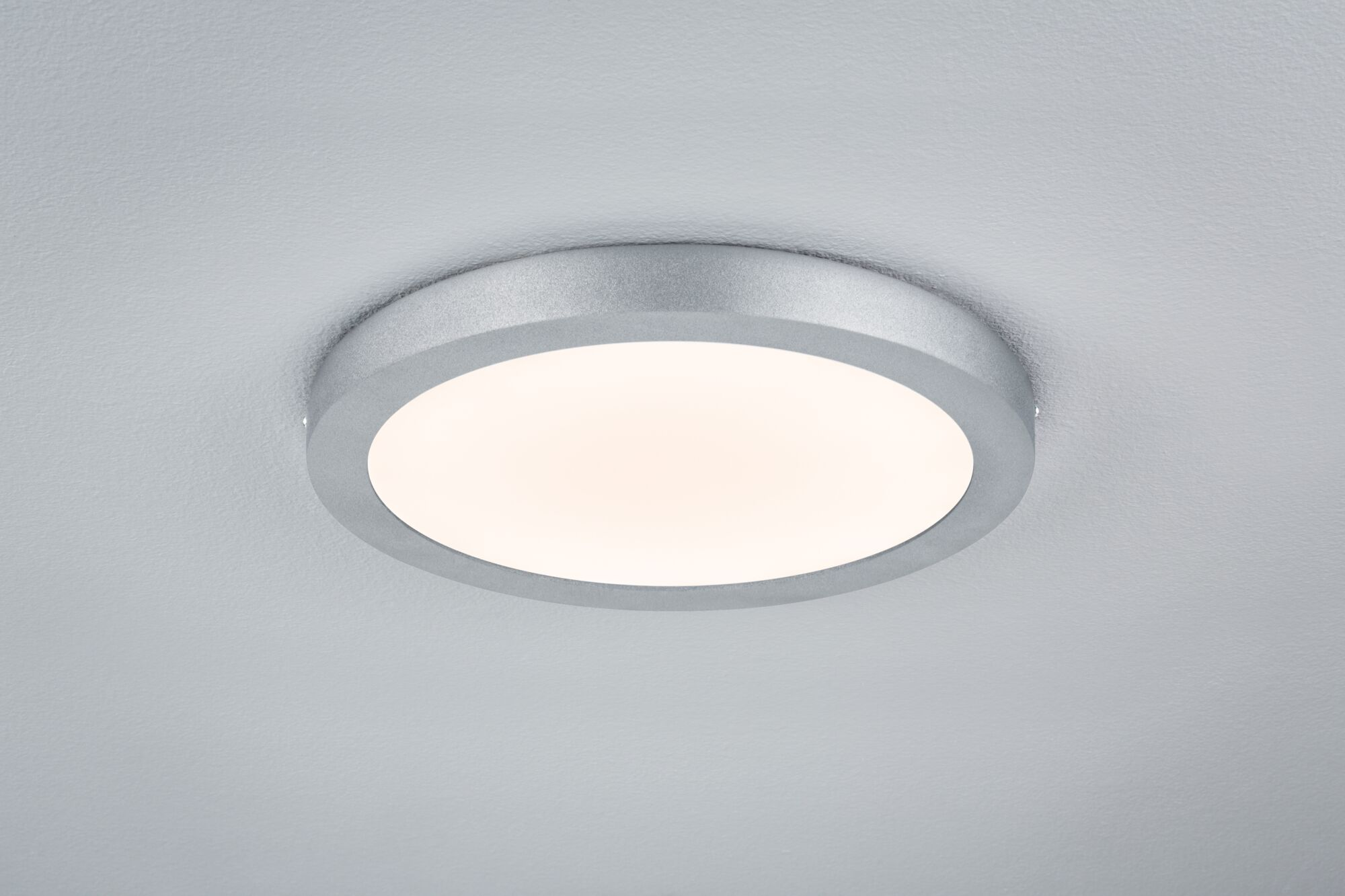 Lampada da soffitto rotonda argentata su soffitto bianco.