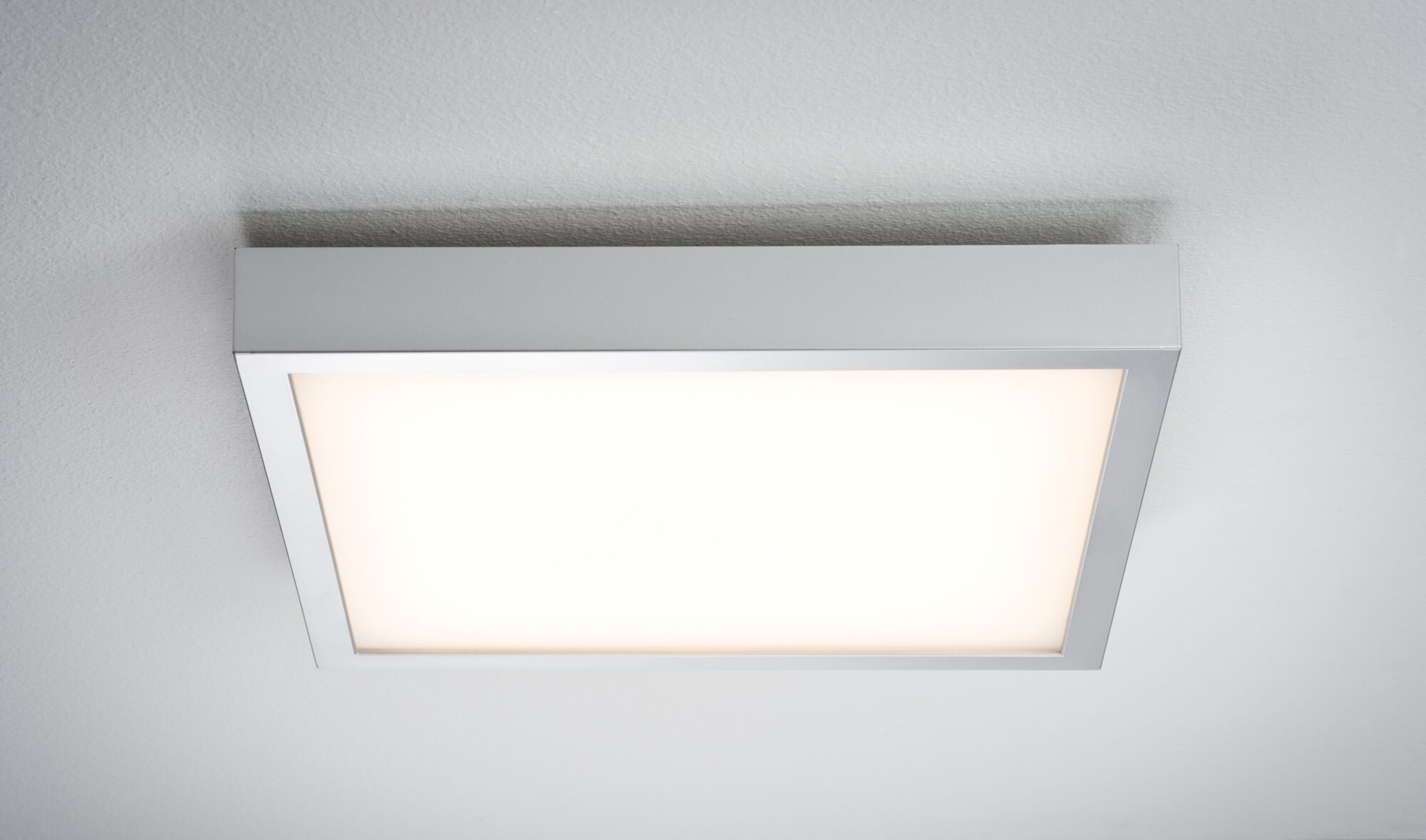 Apparecchio per illuminazione a soffitto quadrato, incassato, cornice argentata, illuminato da luce bianca brillante.