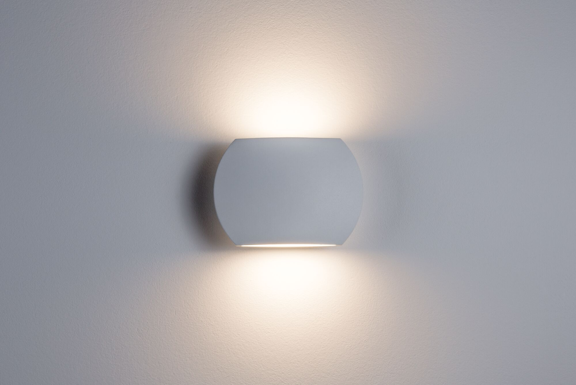 Eine weiße, kugelförmige Wandleuchte, an einer Wand montiert. Sie strahlt ein weiches, warmes Licht aus.