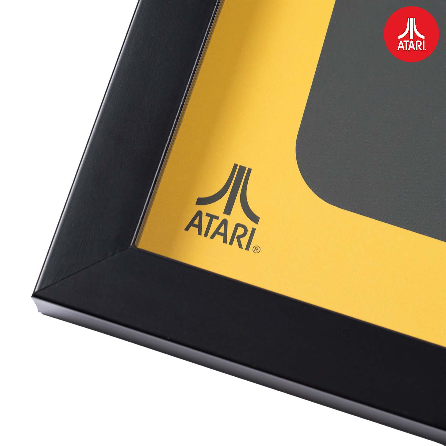 Close-up van een ingelijst Atari-logo op een gele achtergrond. Zwart frame.