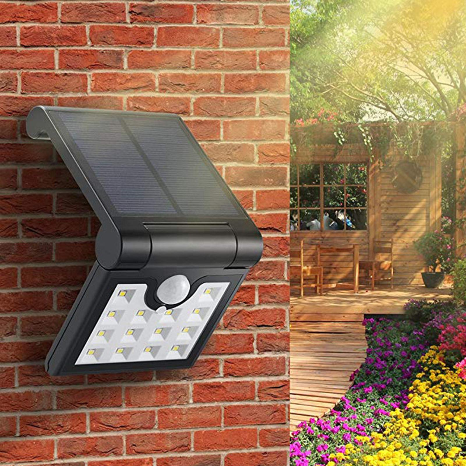 Solarpanel und Leuchte an einer Ziegelmauer befestigt. Ein Garten mit Holzweg im Hintergrund.
