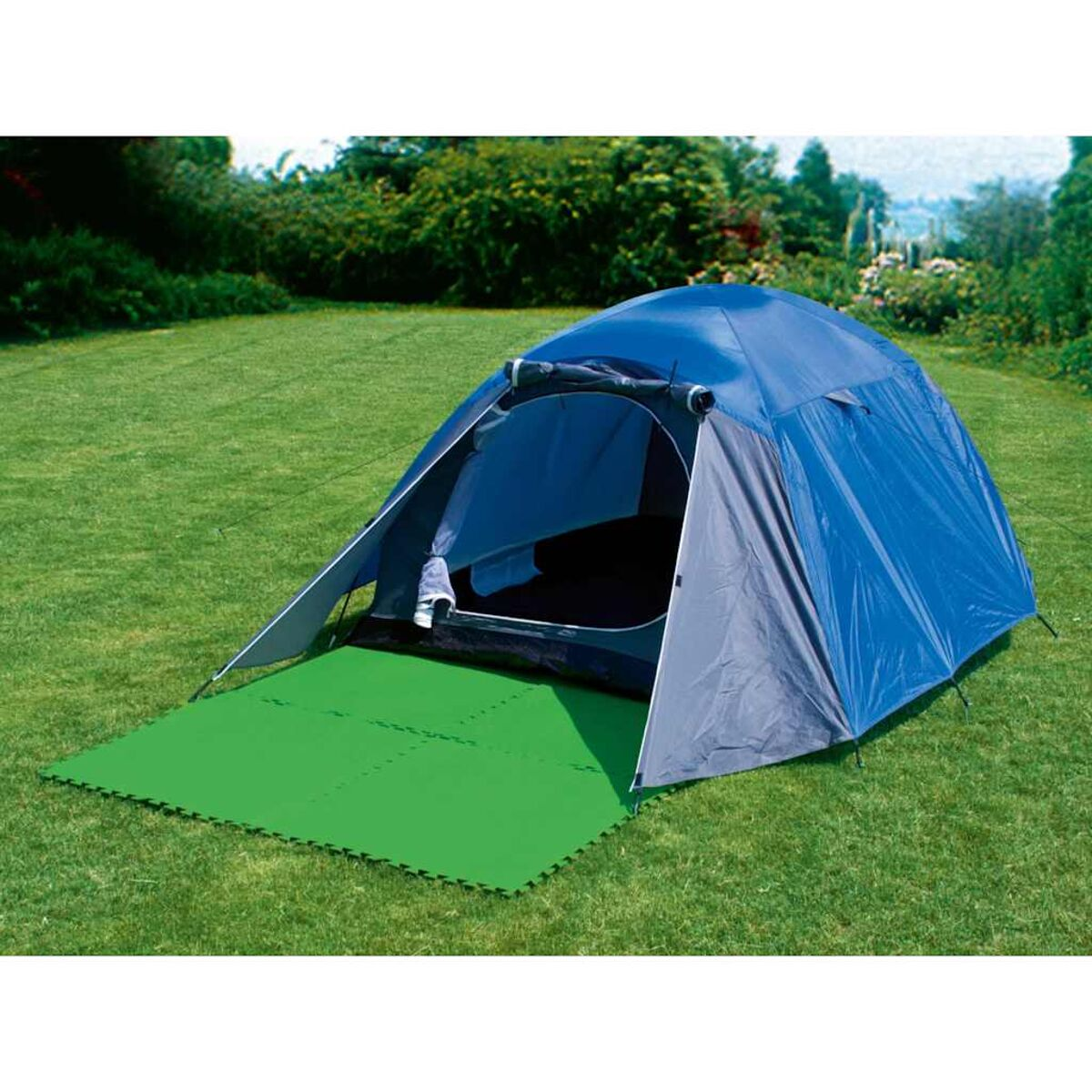 Ein blaues Zelt mit grüner Schaumstoffmatte auf Gras, im Freien aufgebaut.