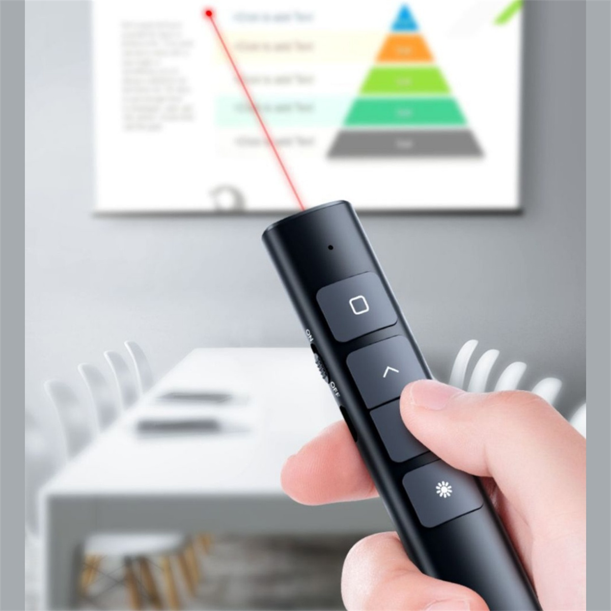 Eine schwarze Präsentationsfernbedienung mit rotem Laserpointer. Eine Hand hält sie. Ein Präsentationsbildschirm ist im Hintergrund.