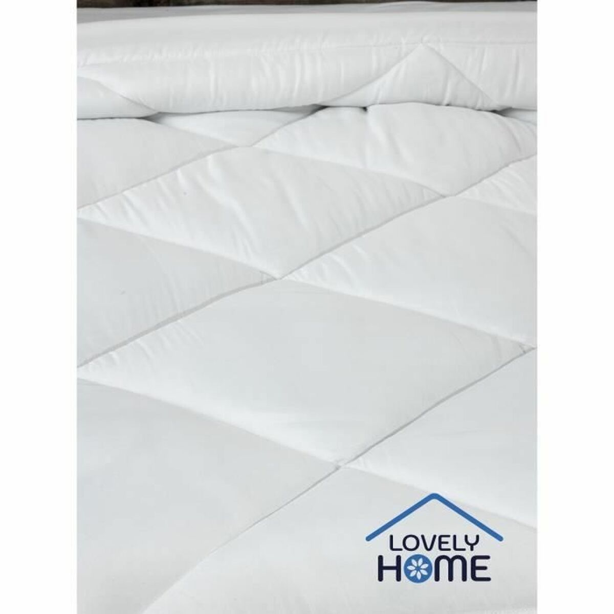 Weiß gesteppter Matratzenschoner auf dem Bett. Der Bezug hat ein Rautenmuster und ein Lovely Home Logo.