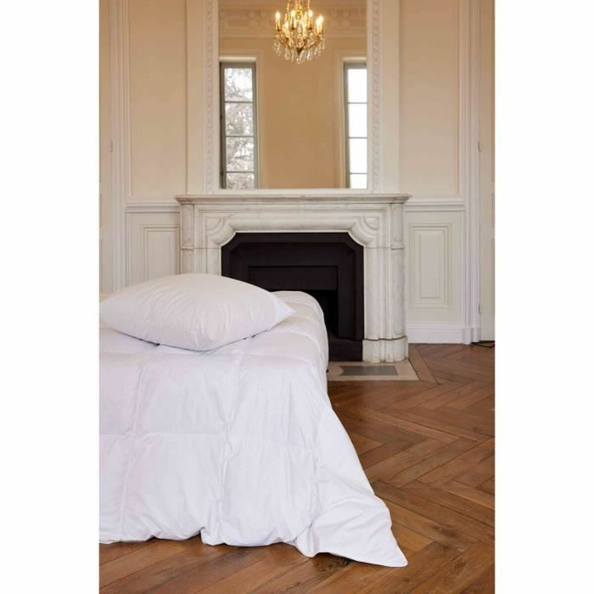 Schlafzimmer mit weißer Bettwäsche auf einem Bett. Kamin und Spiegel im Hintergrund. Holzboden.