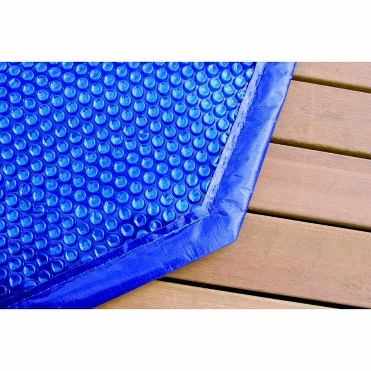 Nahaufnahme einer blauen Blasen-Poolabdeckung auf Holz. Die Blasen sind dicht gepackt.