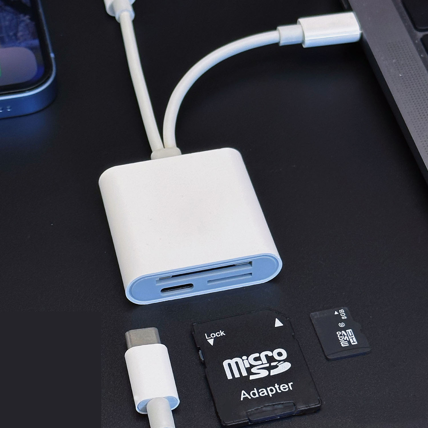 Adapter mit Telefon, SD-Karte und USB-C-Anschluss, alles auf schwarzer Oberfläche. Micro-SD-Karte und Adapter.