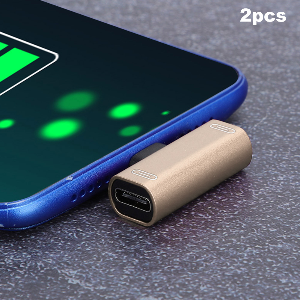 Goldfarbener USB-C-auf-Lightning-Adapter, der in ein blaues Telefon gesteckt ist. 2 Stück werden gezeigt.