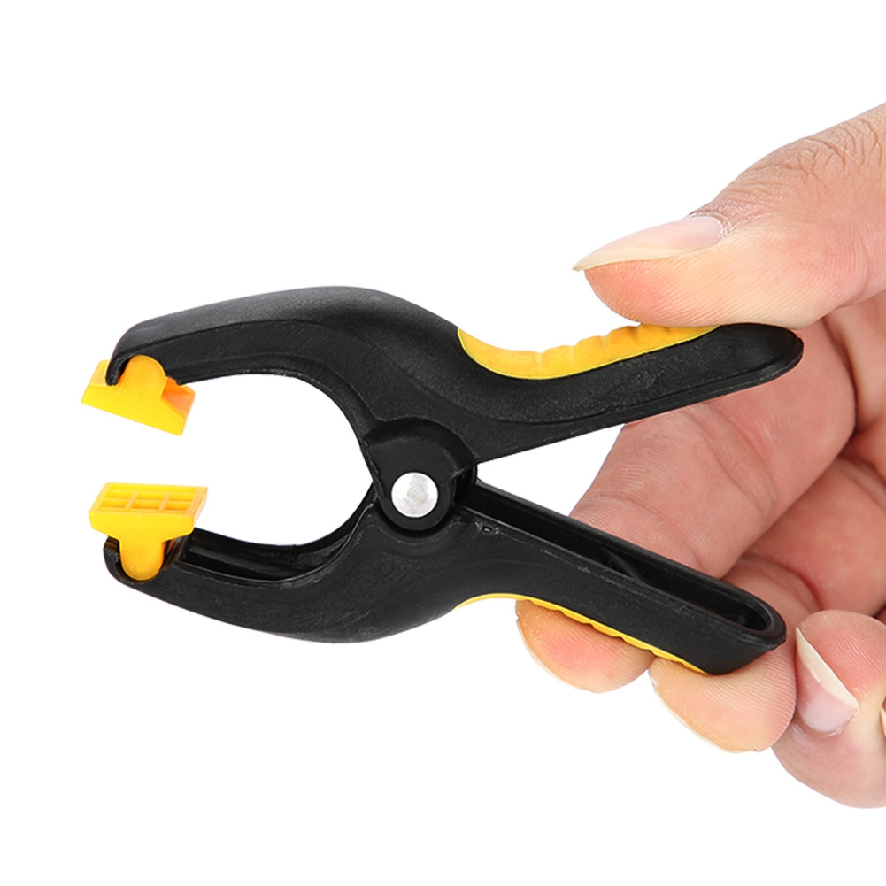 Eine schwarz-gelbe Klemme wird von einer Hand gehalten. Gelbe Teile sind sichtbar.