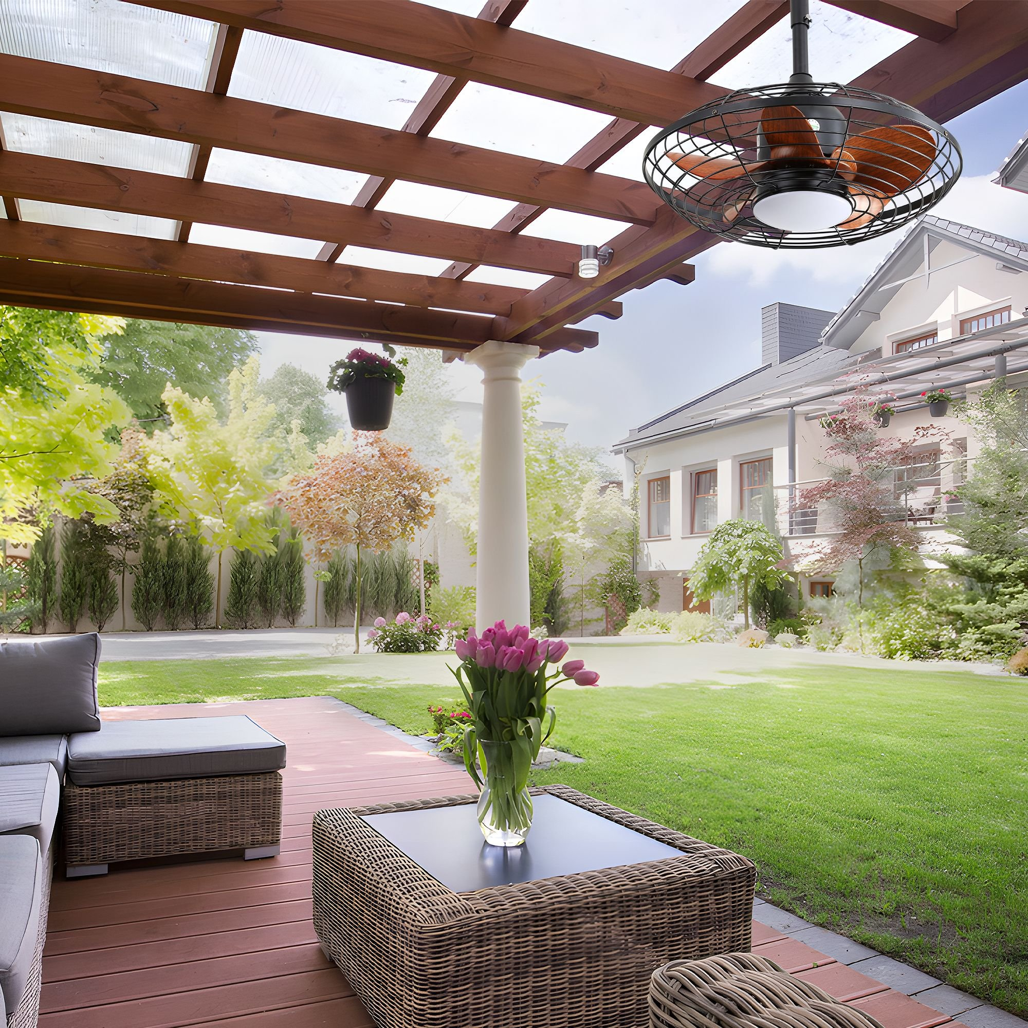 Eine Terrasse mit Deckenventilator, Tisch mit Blumen und Haus im Hintergrund.