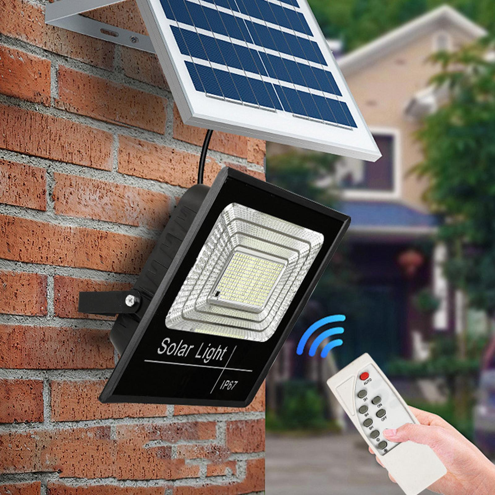 Eine Solarlampe an einer Backsteinmauer, mit Fernbedienung in der Hand. Das Sonnenkollektor befindet sich oben.