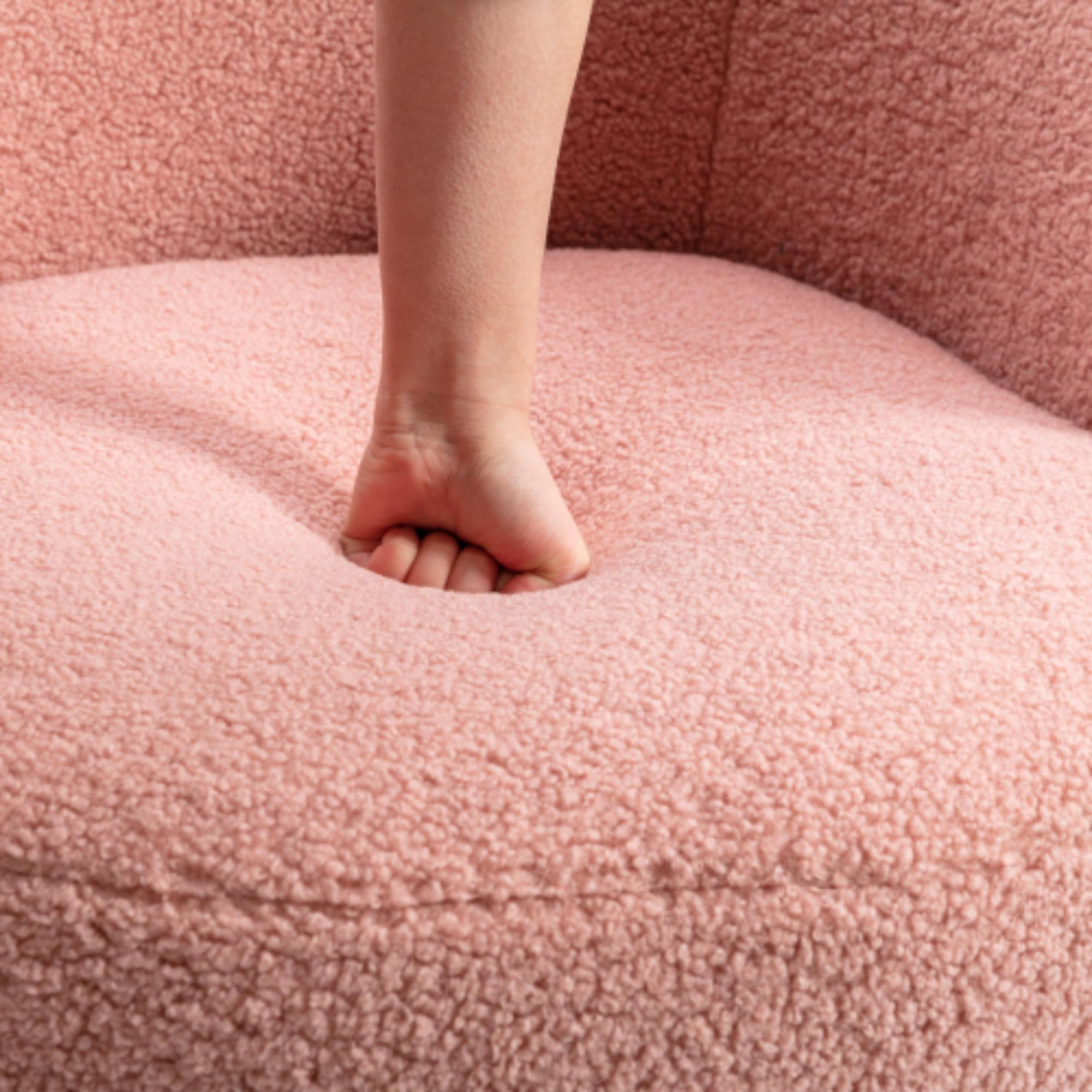 Eine Hand drückt in den rosa, flauschigen Stuhl und komprimiert das Material.