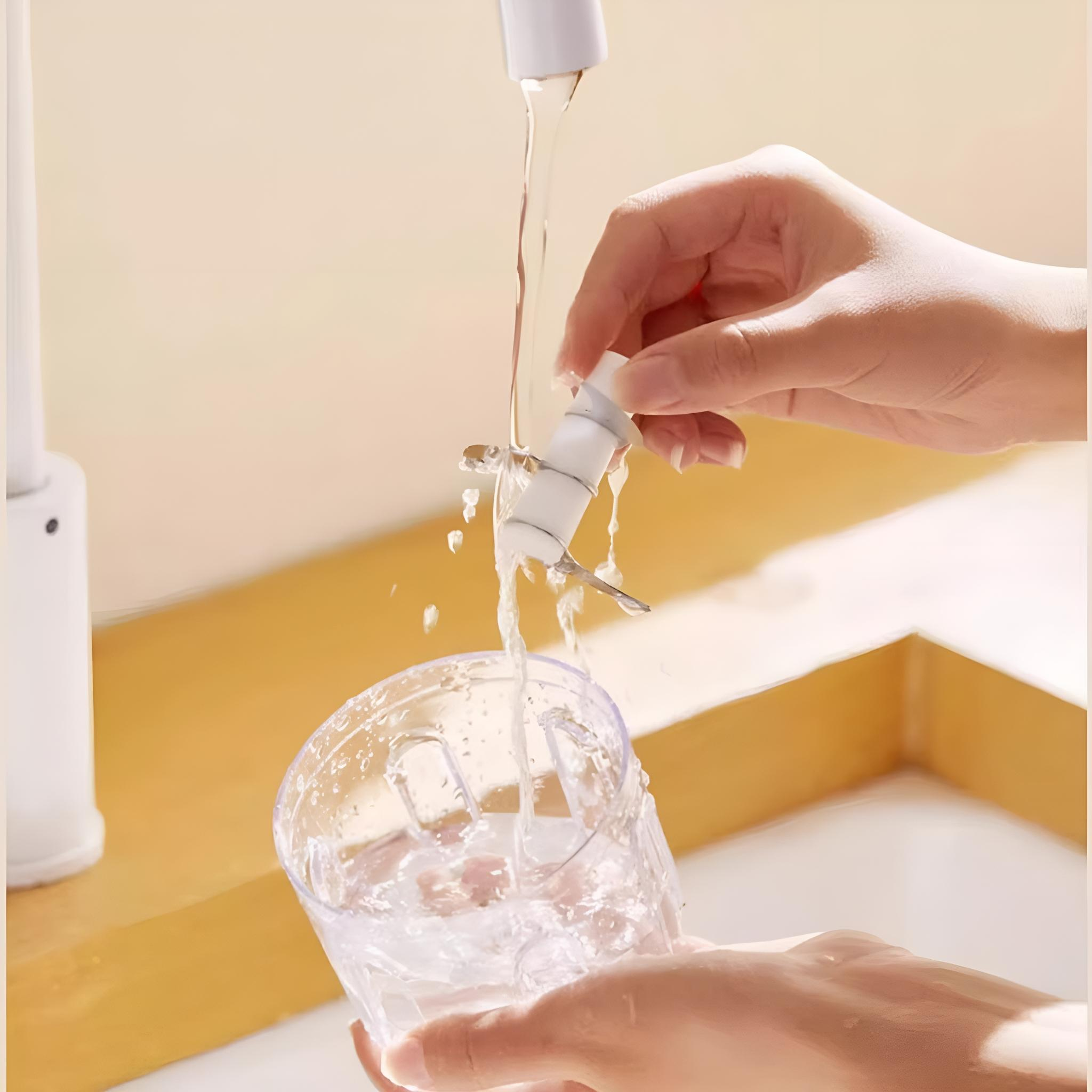 Hände einer Person, die einen kleinen Lebensmittelzerkleinerer unter einem Wasserhahn mit Wasser spülen.