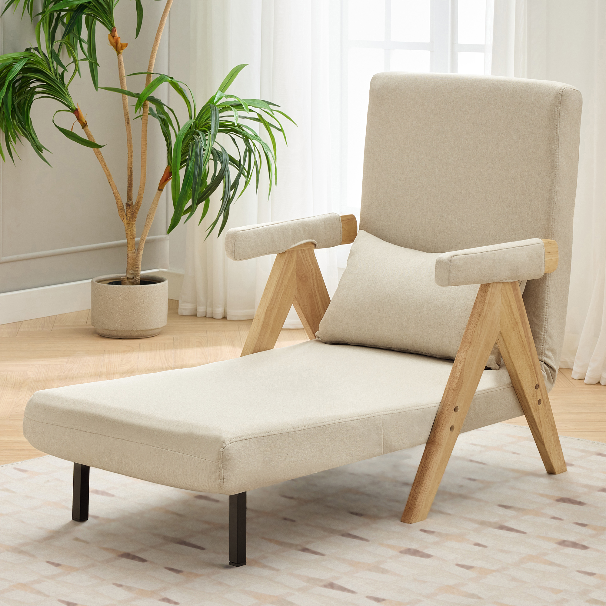 Beige Chaiselongue mit Kissen und Holzrahmen, neben einer Pflanze und einem Teppich auf dem Boden.