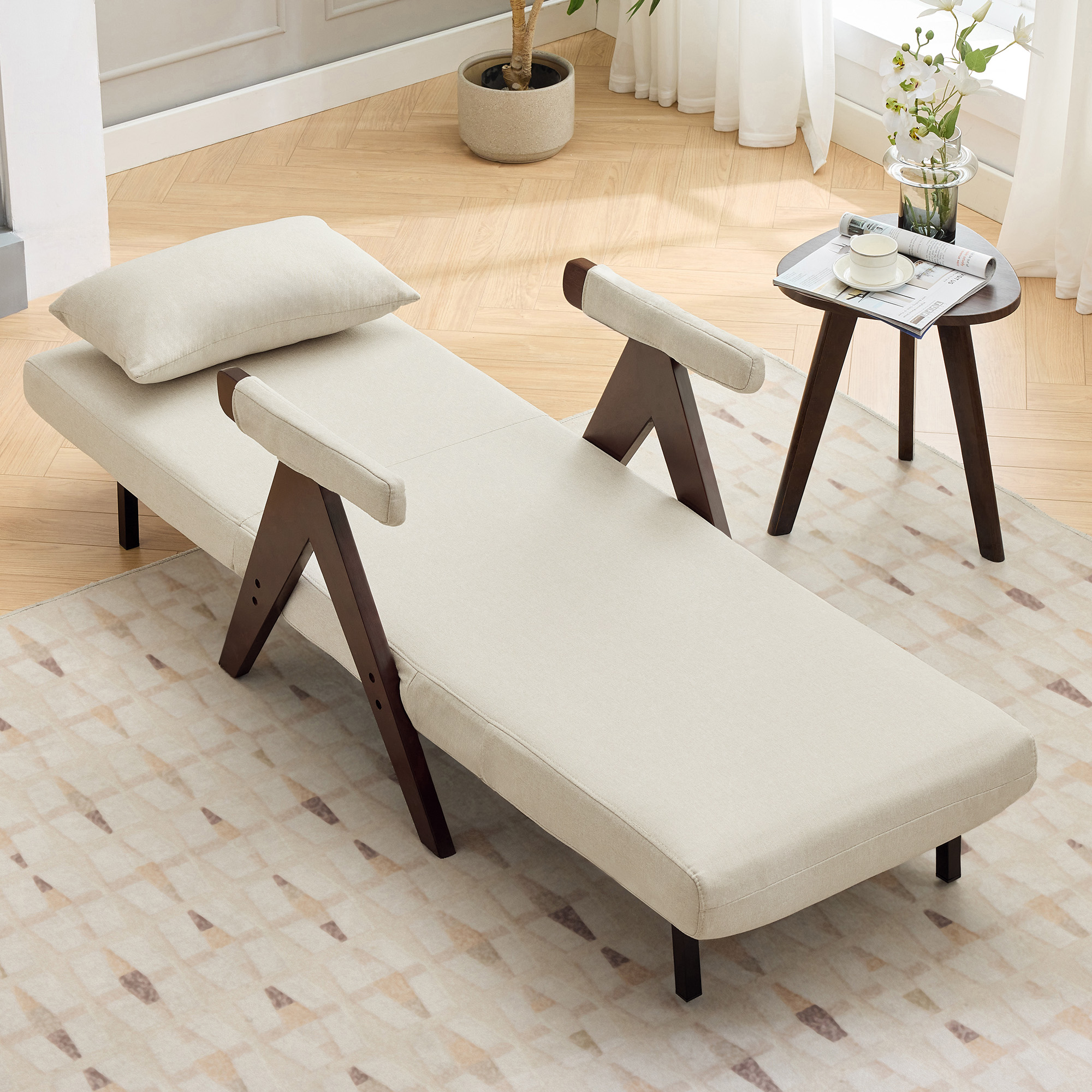 Beige Chaiselongue mit braunen Holzbeinen und Armlehnen. Ein Kissen liegt auf dem Sitz. Couchtisch.