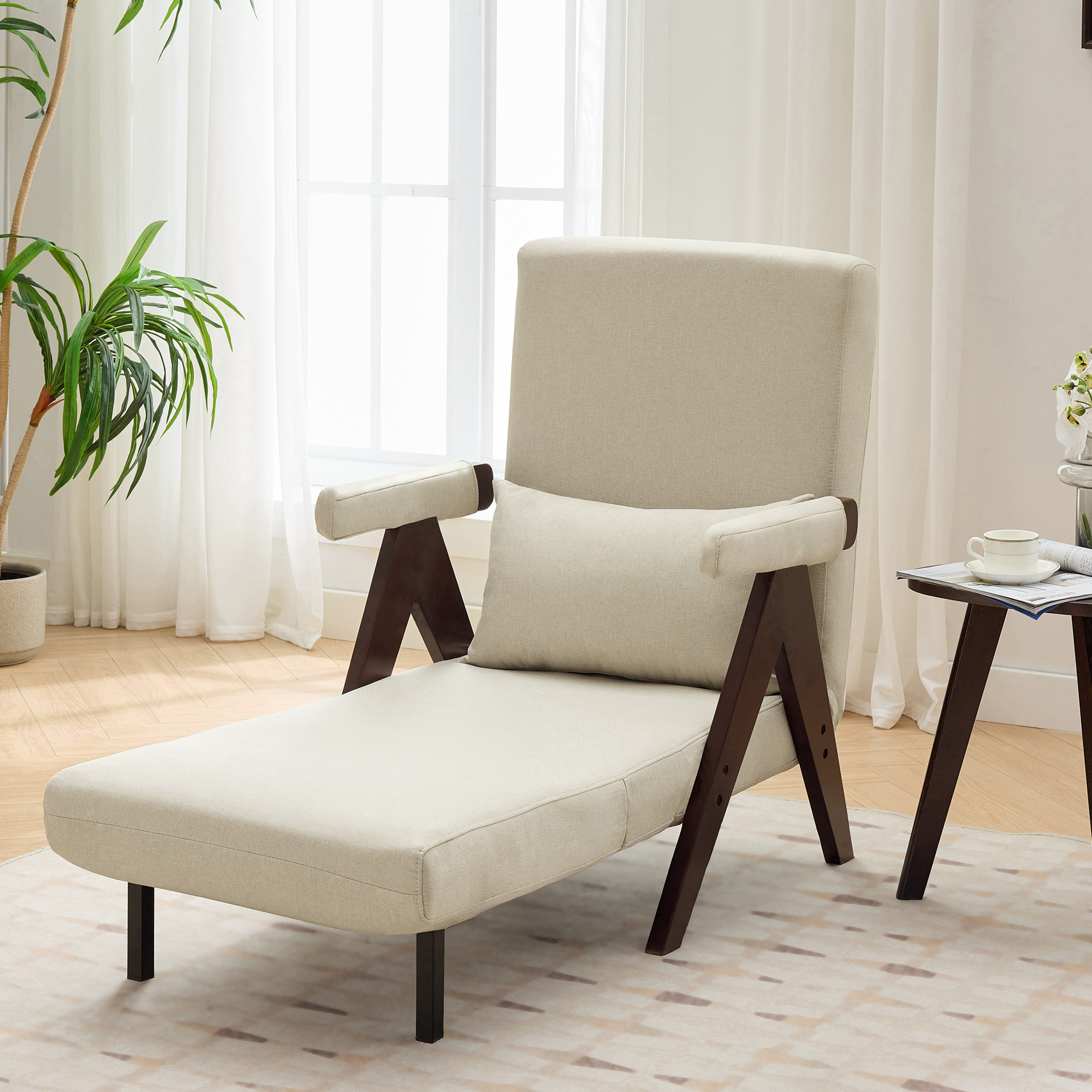 Beige Chaiselongue mit braunen Holzbeinen und Armlehnen. Ein Kissen liegt auf dem Sitz, am Fenster.
