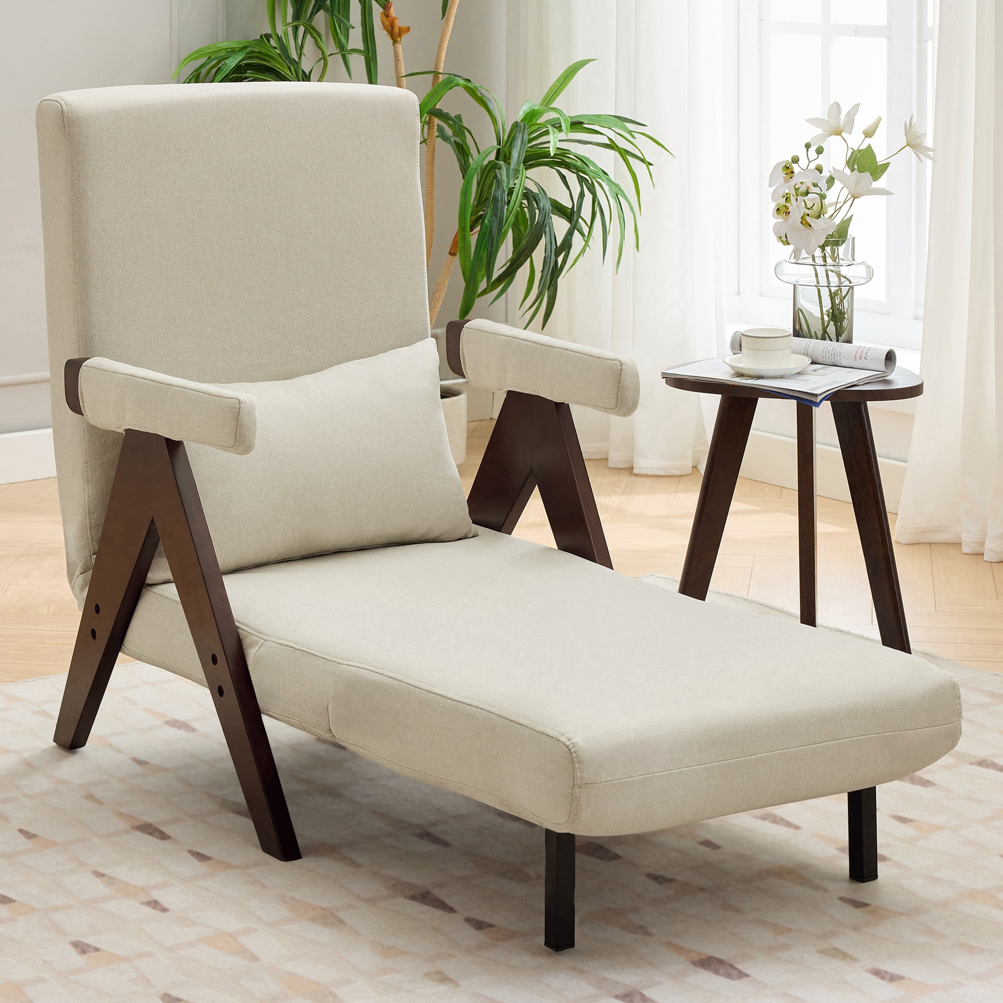 Eine beige Chaiselongue mit kleinem runden Tisch und einer Pflanze am Fenster.