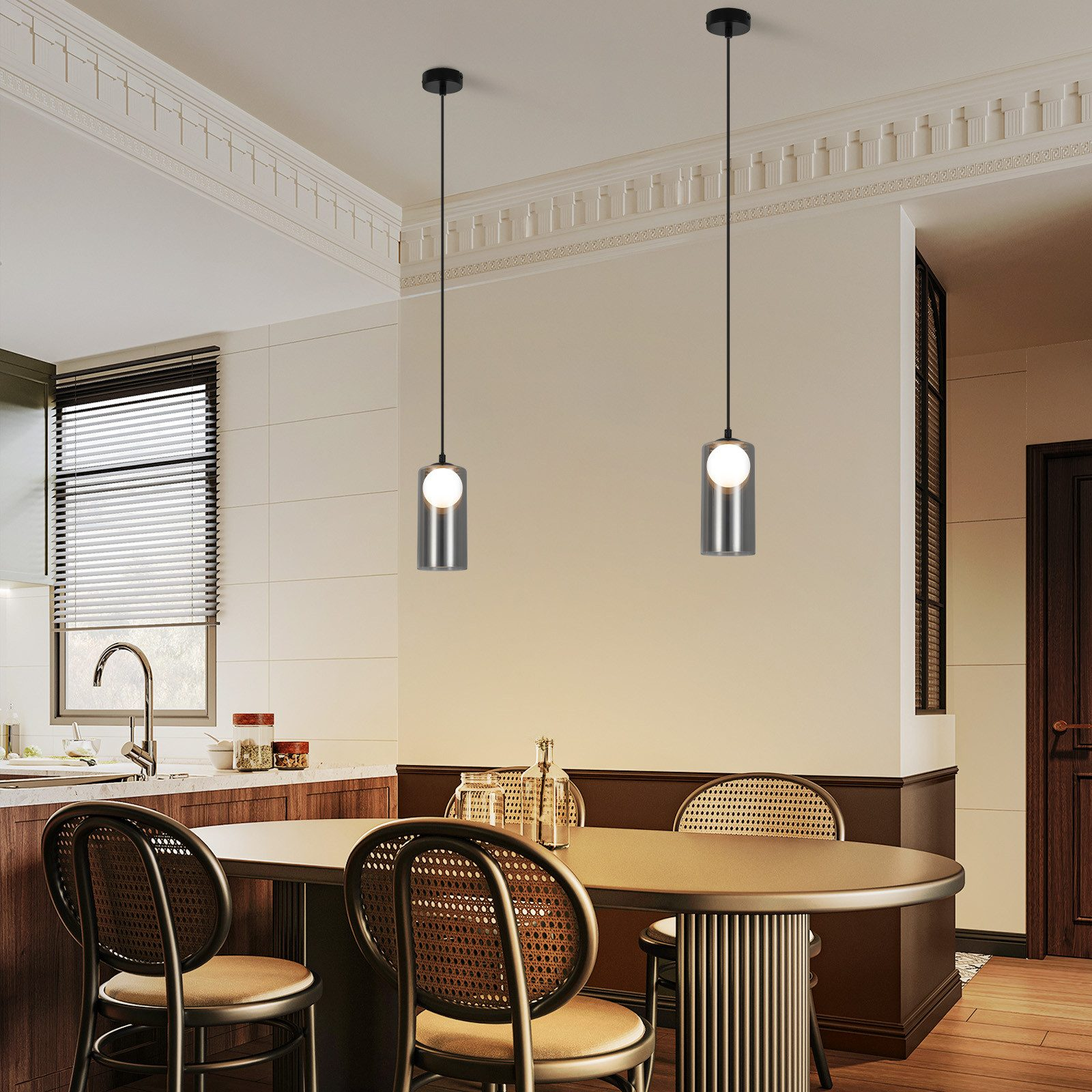 Cucina con lampade a sospensione. Due luci cilindriche pendono sopra un tavolo da pranzo. Tonalità neutre, pareti bianche, dettagli in legno.