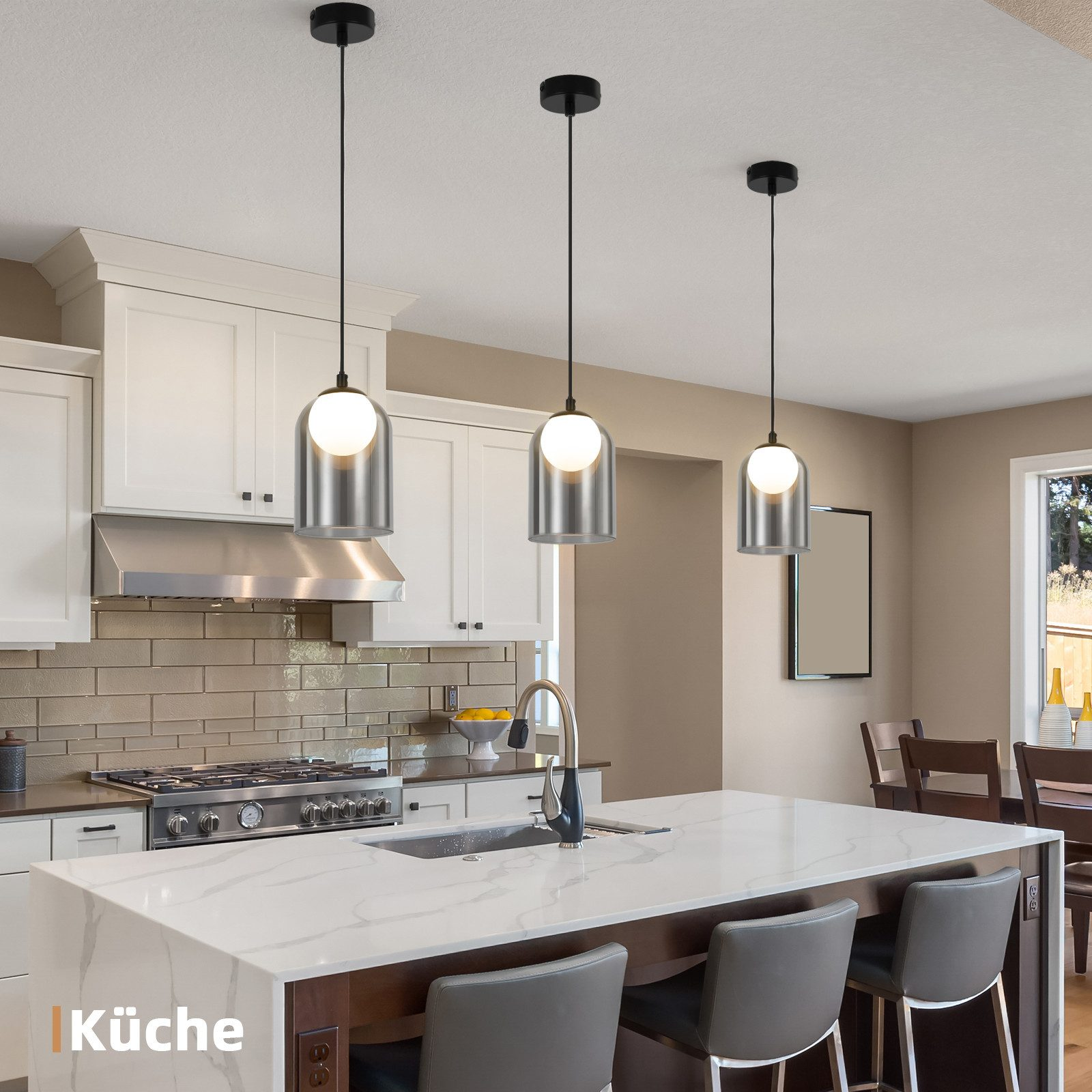Tre lampade a sospensione con paralumi in vetro sopra un'isola cucina con sgabelli, design moderno.