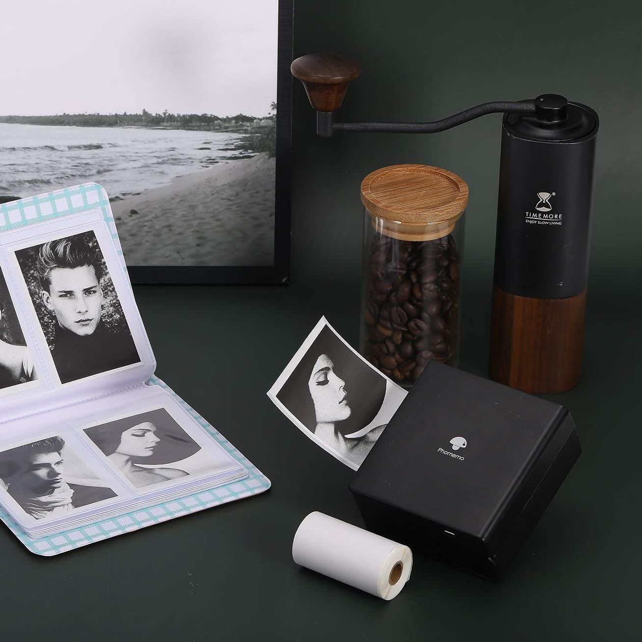 Ein Fotoalbum mit Fotos, eine Kaffeemühle und ein schwarzer Drucker mit einer Papierrolle.