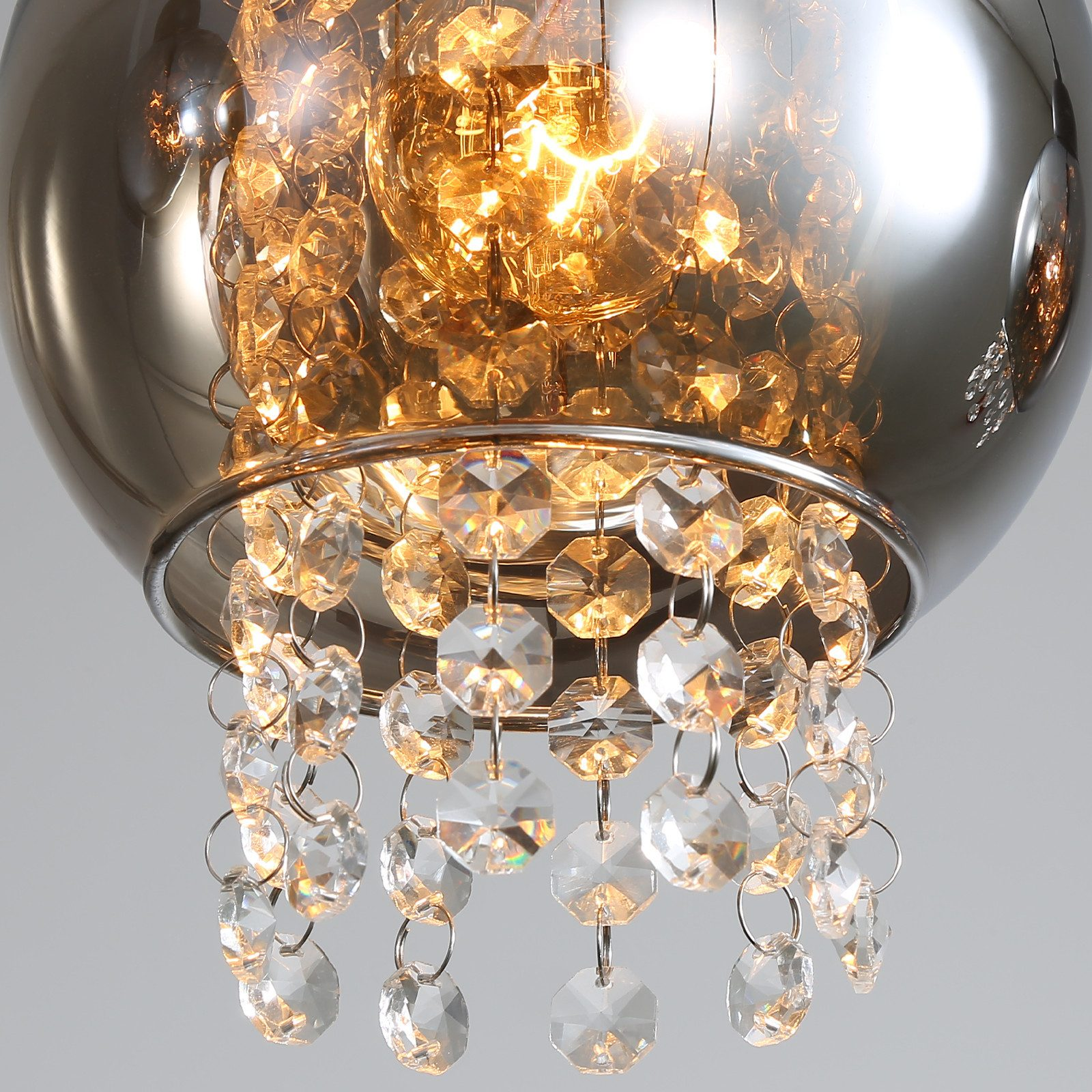 Primo piano di una lampada a sospensione con dettagli in cristallo, che mostra i dettagli del design della luce.