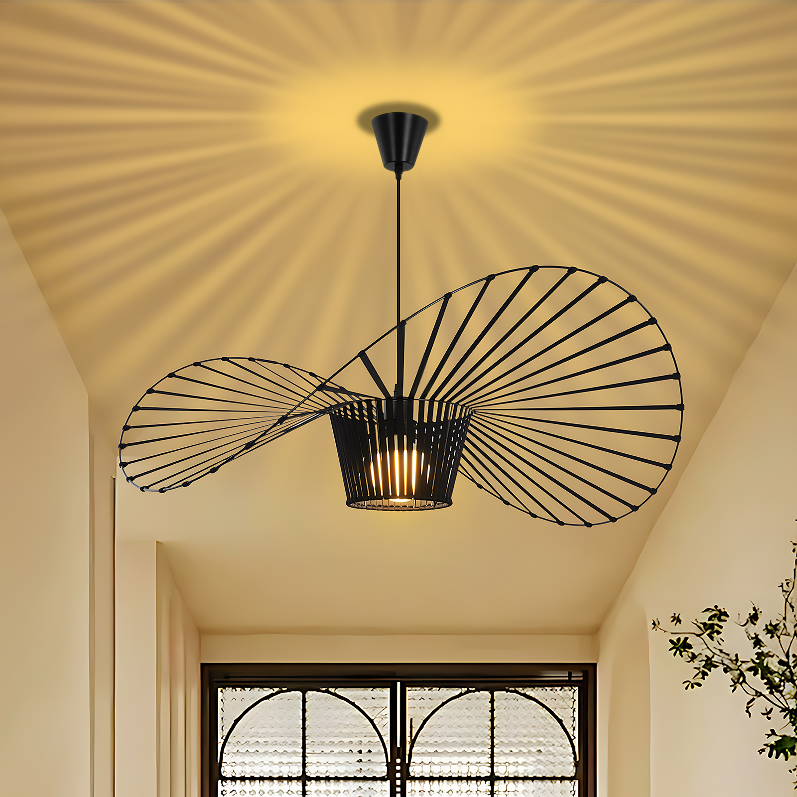 Una lampada a sospensione con un design nero a forma di cappello, che illumina un corridoio. La luce irradia dall'apparecchio.