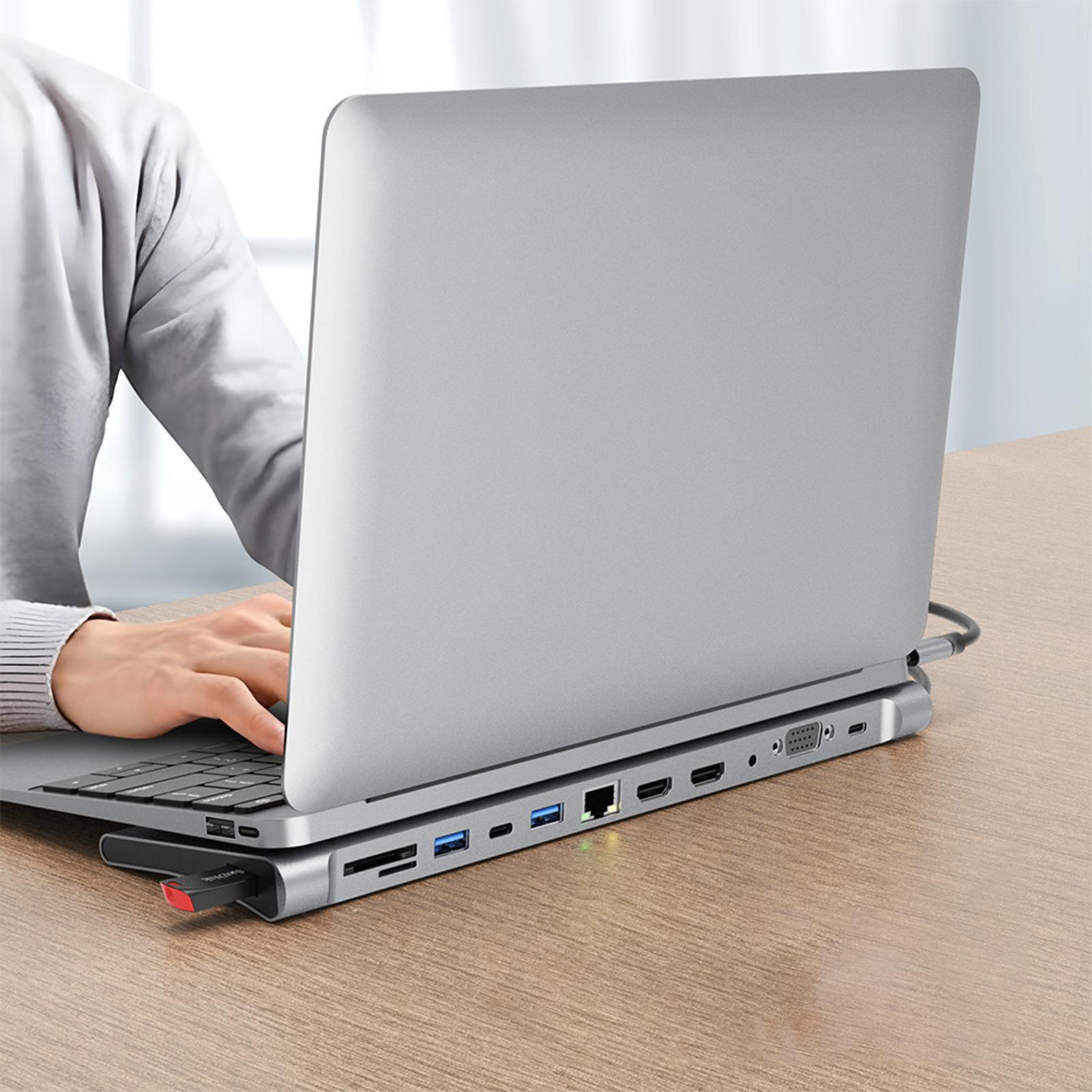 Laptop mit silbernem USB-Hub verbunden. Eine Hand tippt auf der Tastatur. Ein roter USB-Stick ist eingesteckt.