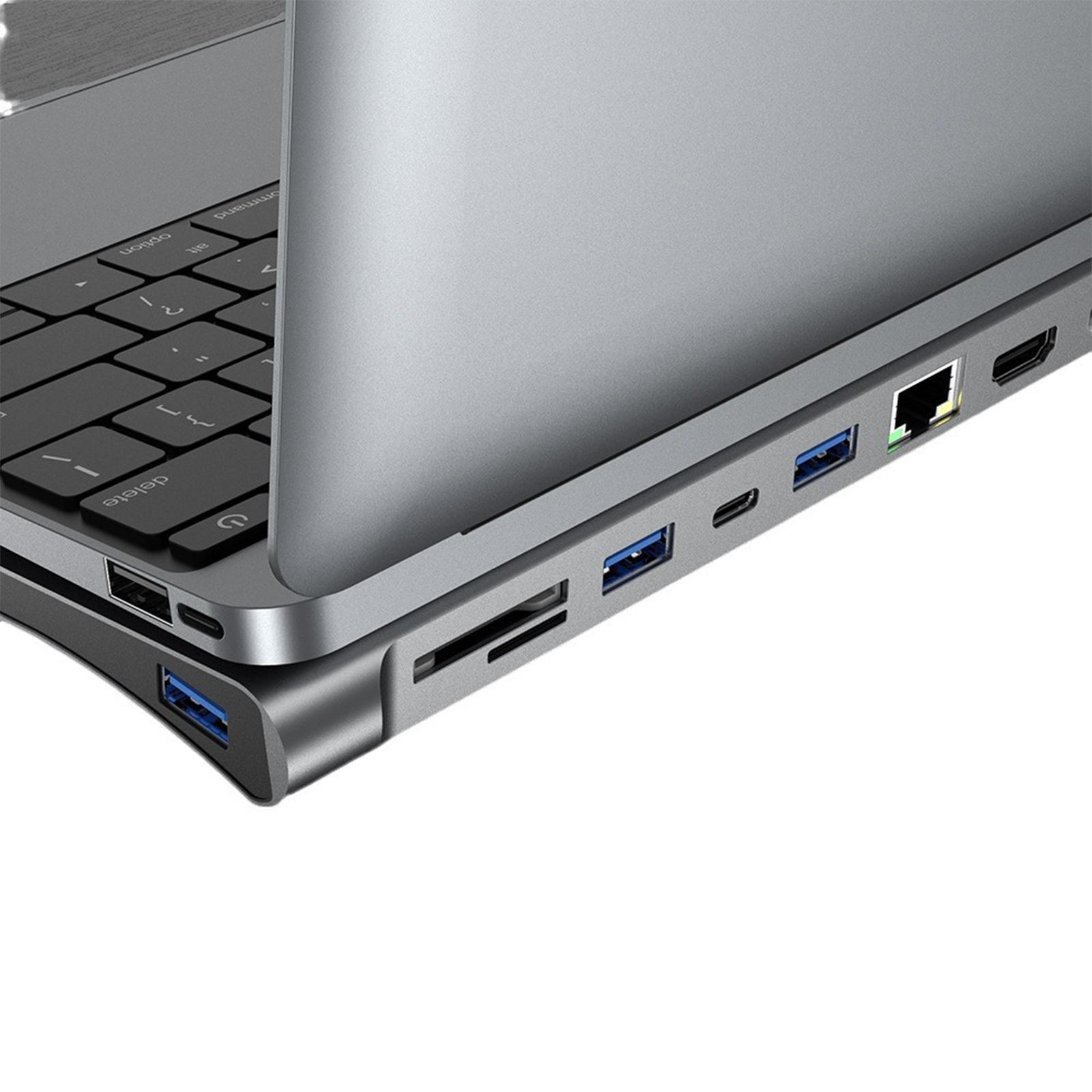 Nahaufnahme eines Laptops, der mit einem USB-Hub mit verschiedenen Anschlüssen verbunden ist. Das Gerät steht auf einem Holztisch.
