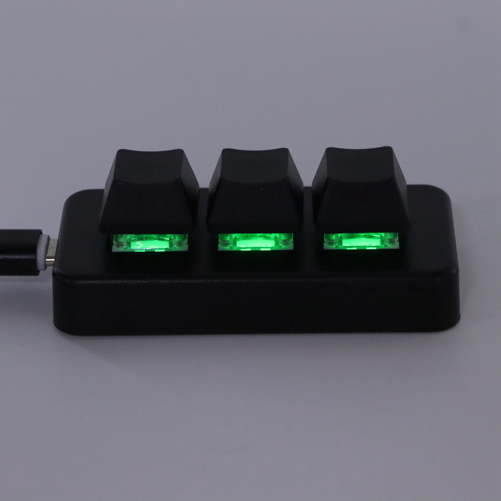 Drei schwarze mechanische Tastaturschalter, jeder mit einer grünen LED-Leuchte.
