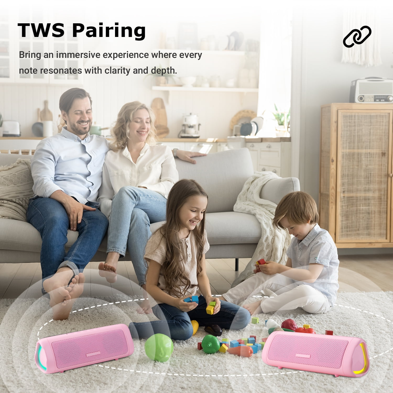 Familie spielt mit rosa Lautsprechern. Zwei rosa Lautsprecher auf dem Boden. Personen im Hintergrund.