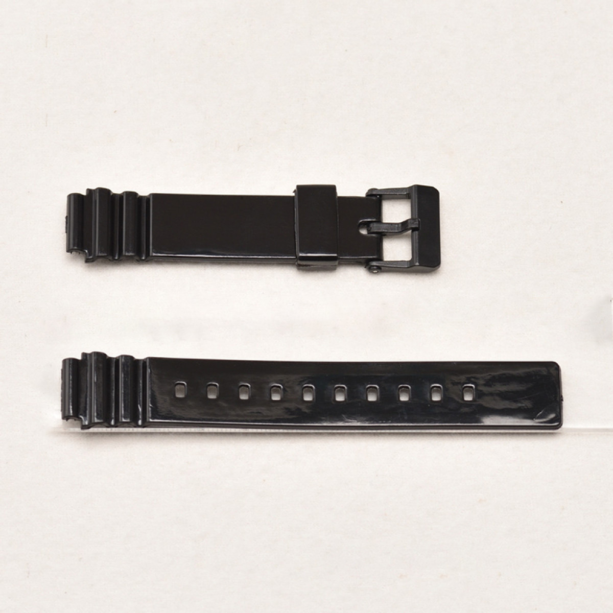 Zwei schwarze Uhrenarmbänder. Eines mit Schnalle, das andere mit Löchern für den Schnallenstift. Weißer Hintergrund.