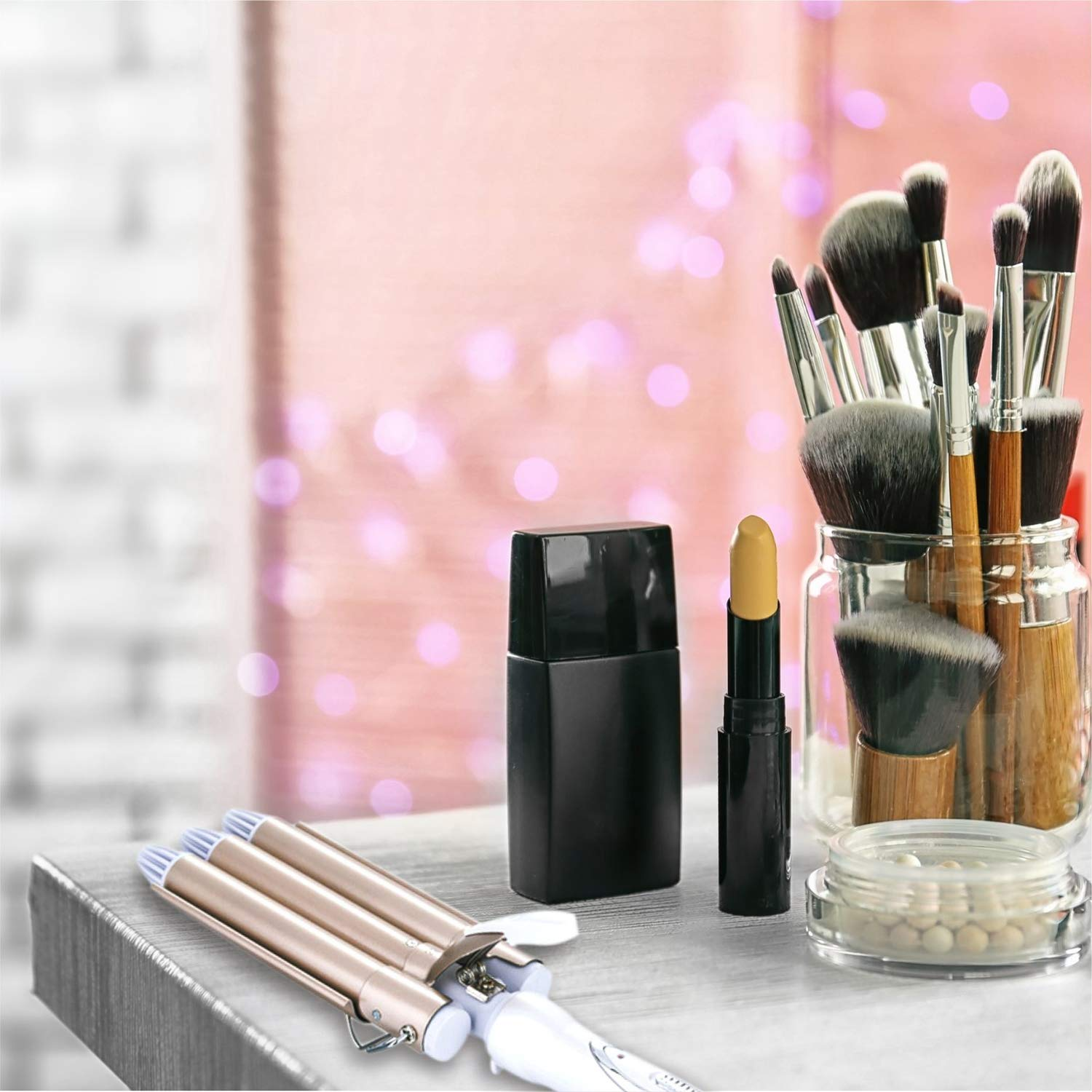 Lockenstab und Make-up-Zubehör, einschließlich Pinsel und Lippenstift auf einem Tisch.