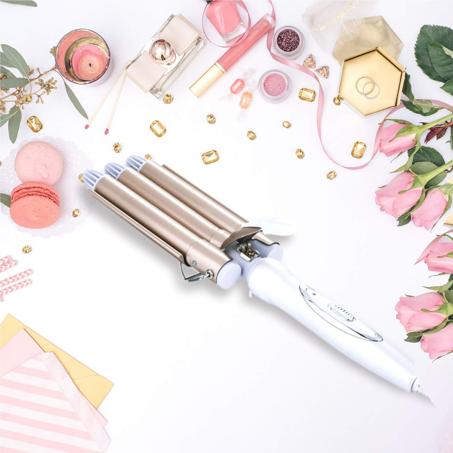Lockenstab mit Haarprodukten und Accessoires auf einer weißen Oberfläche.