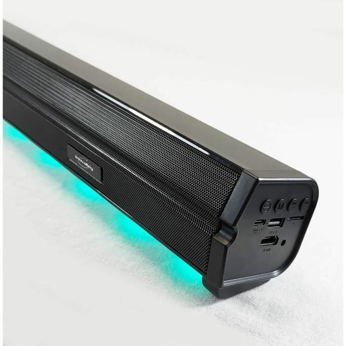 Schwarze Soundbar mit Mesh-Front, die grünes Licht emittiert, und ein paar Knöpfe an der Seite.