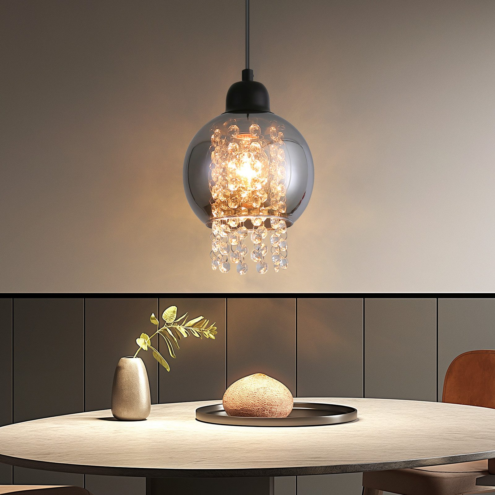 Lampada a sospensione con globo di vetro e cristalli, su tavolo da pranzo.