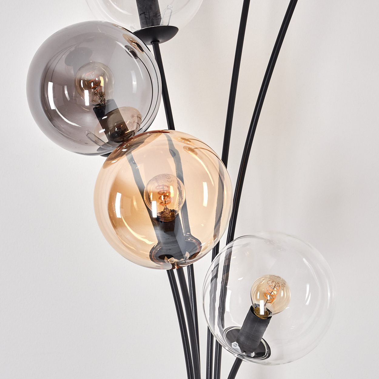 Nahaufnahme einer modernen Stehlampe mit mehreren kugelförmigen Glasschirmen, die jeweils eine Glühbirne enthalten.