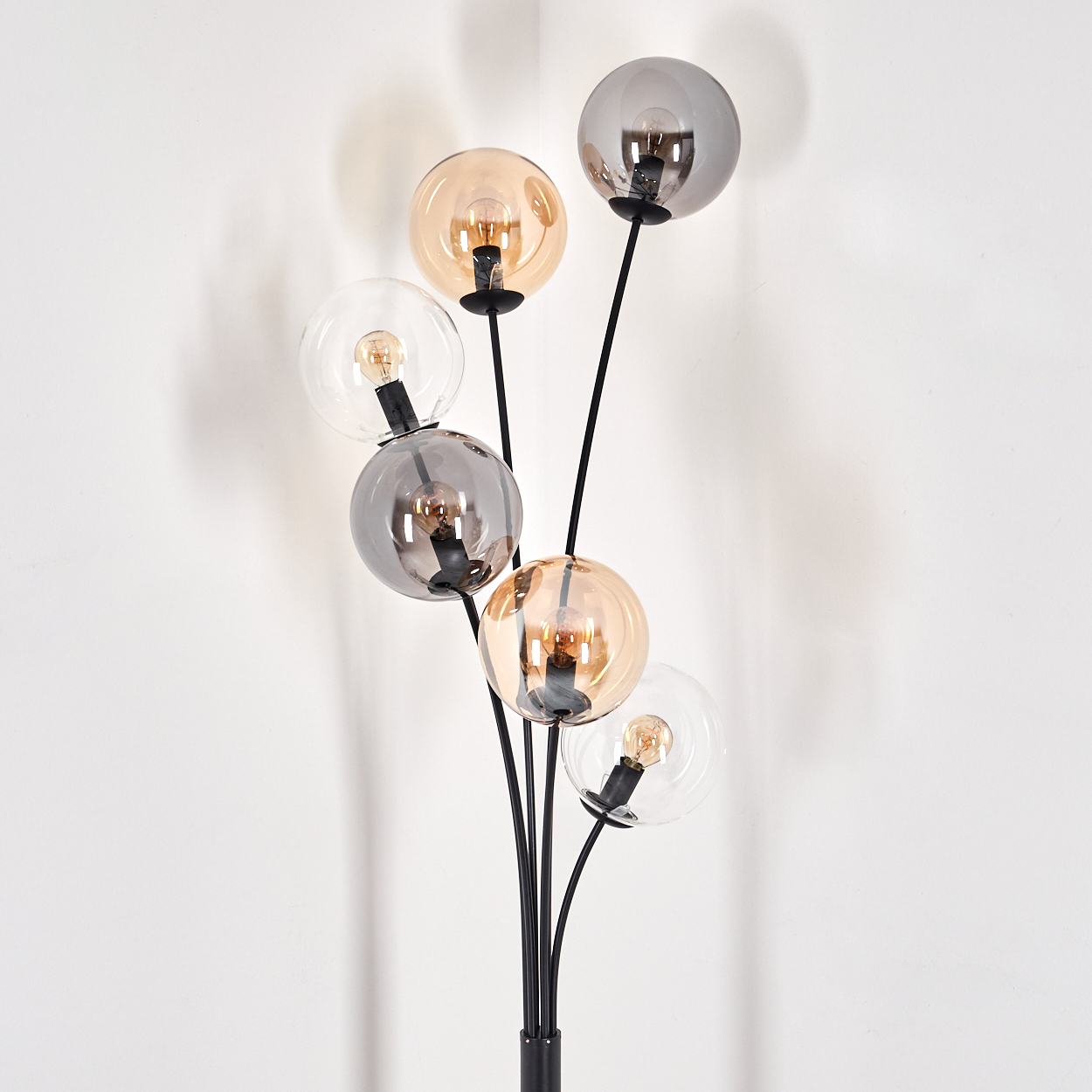 Eine moderne Stehlampe mit mehreren Glaskolben in verschiedenen Farben, vor weißem Hintergrund.