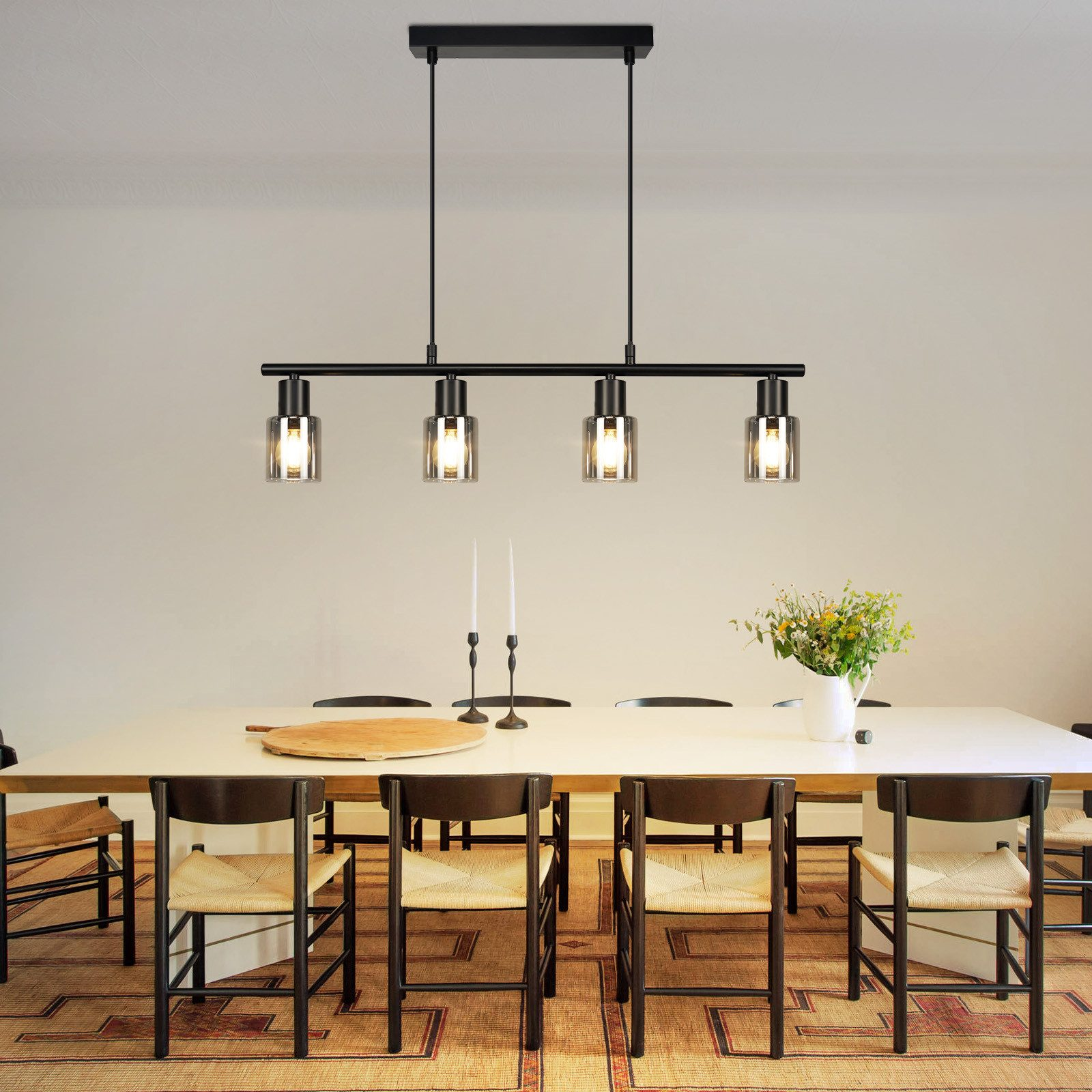 Sala da pranzo con tavolo e sedie e quattro lampade a sospensione cilindriche.