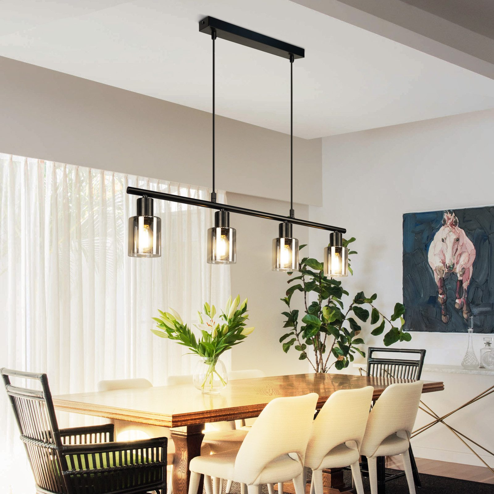 Quattro lampade a sospensione con paralumi cilindrici in vetro in una sala da pranzo.