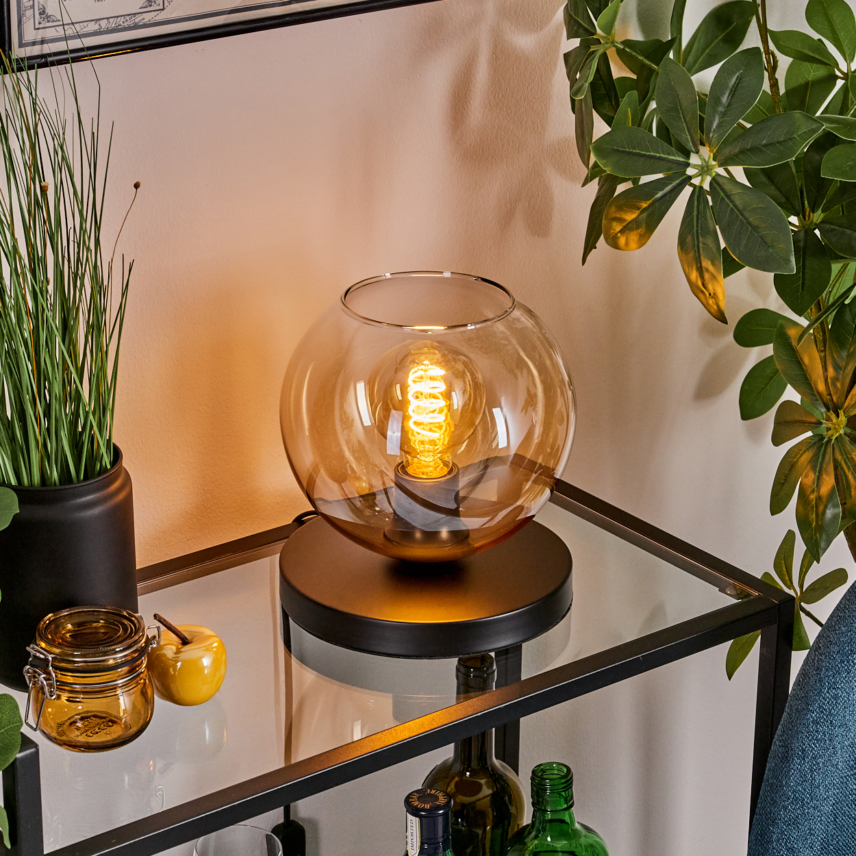 Eine Tischlampe mit Glassphärenschirm und Edison-Glühbirne.