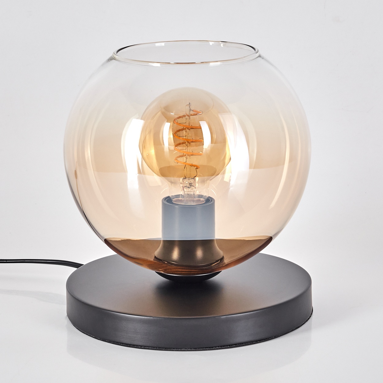 Eine Lampe mit dunklem Sockel, rundem Glasschirm und sichtbarer Glühbirne.